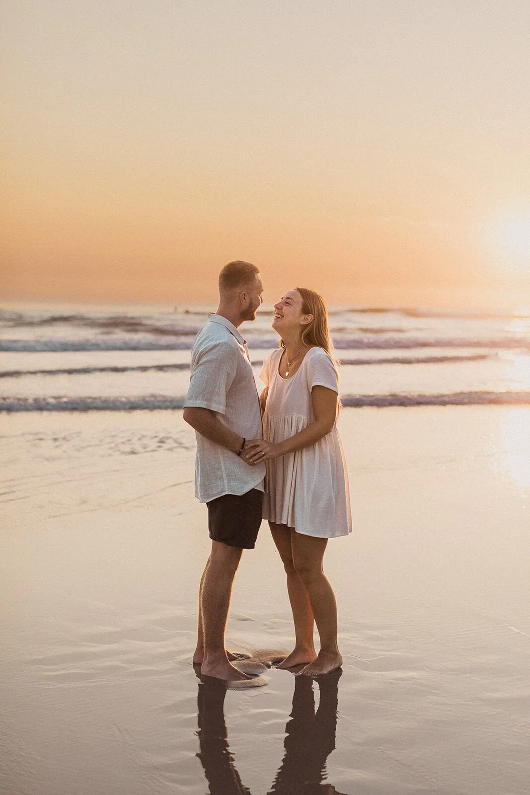 Couple standing with foreheads together in front of the waves, Charlie and Hannah's sunrise marriage proposal at Broken Head Beach, Byron Bay