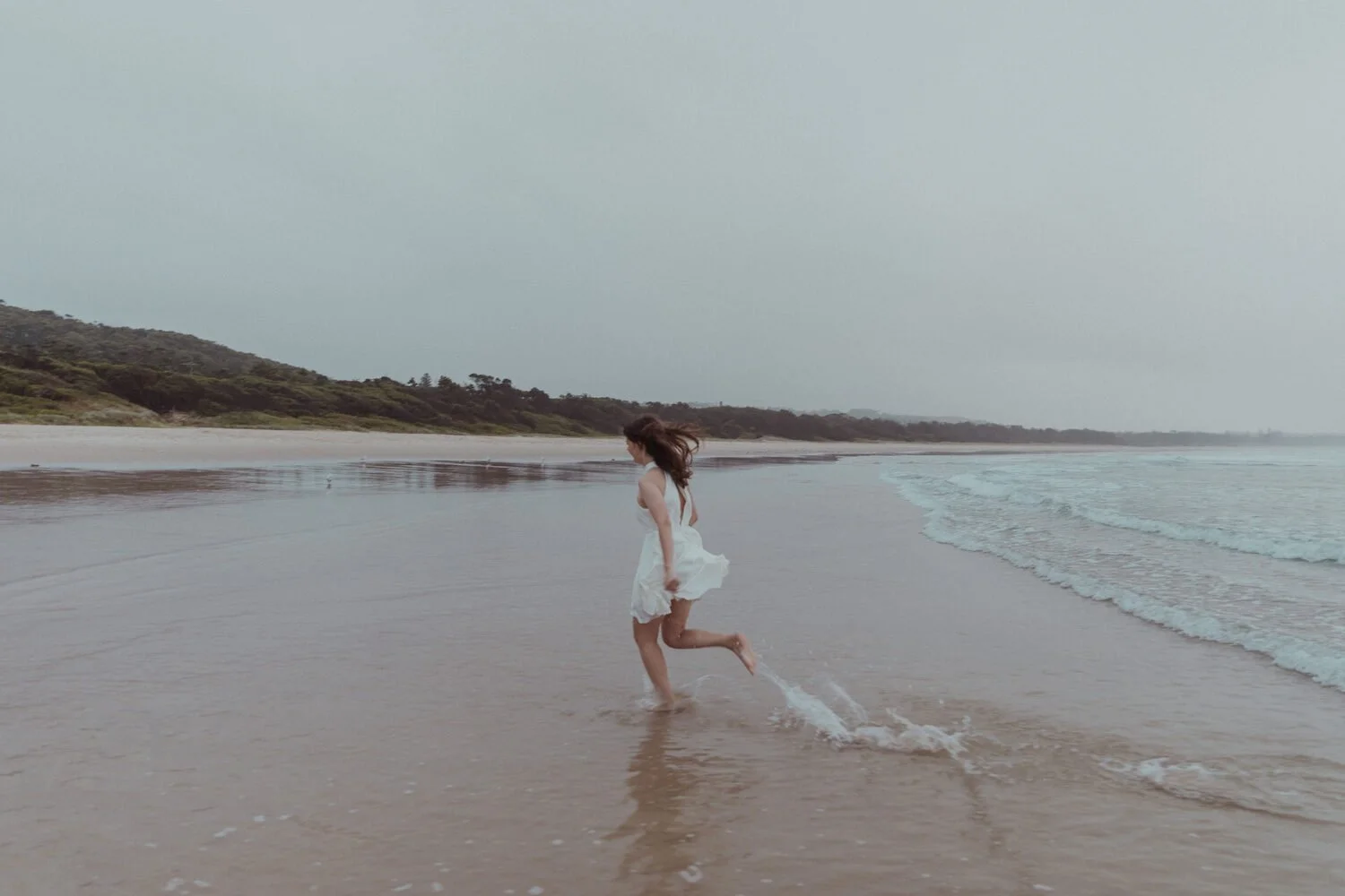 Bride running through the shallows, Yoanne and Elisa's rainy elopement at Broken Head, Byron Bay