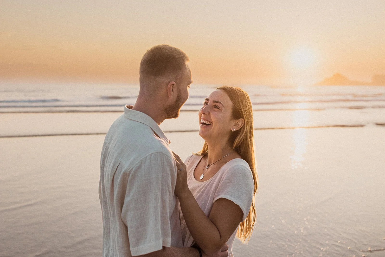 Couple laughing together at the water's edge, Charlie and Hannah's sunrise marriage proposal at Broken Head Beach, Byron Bay