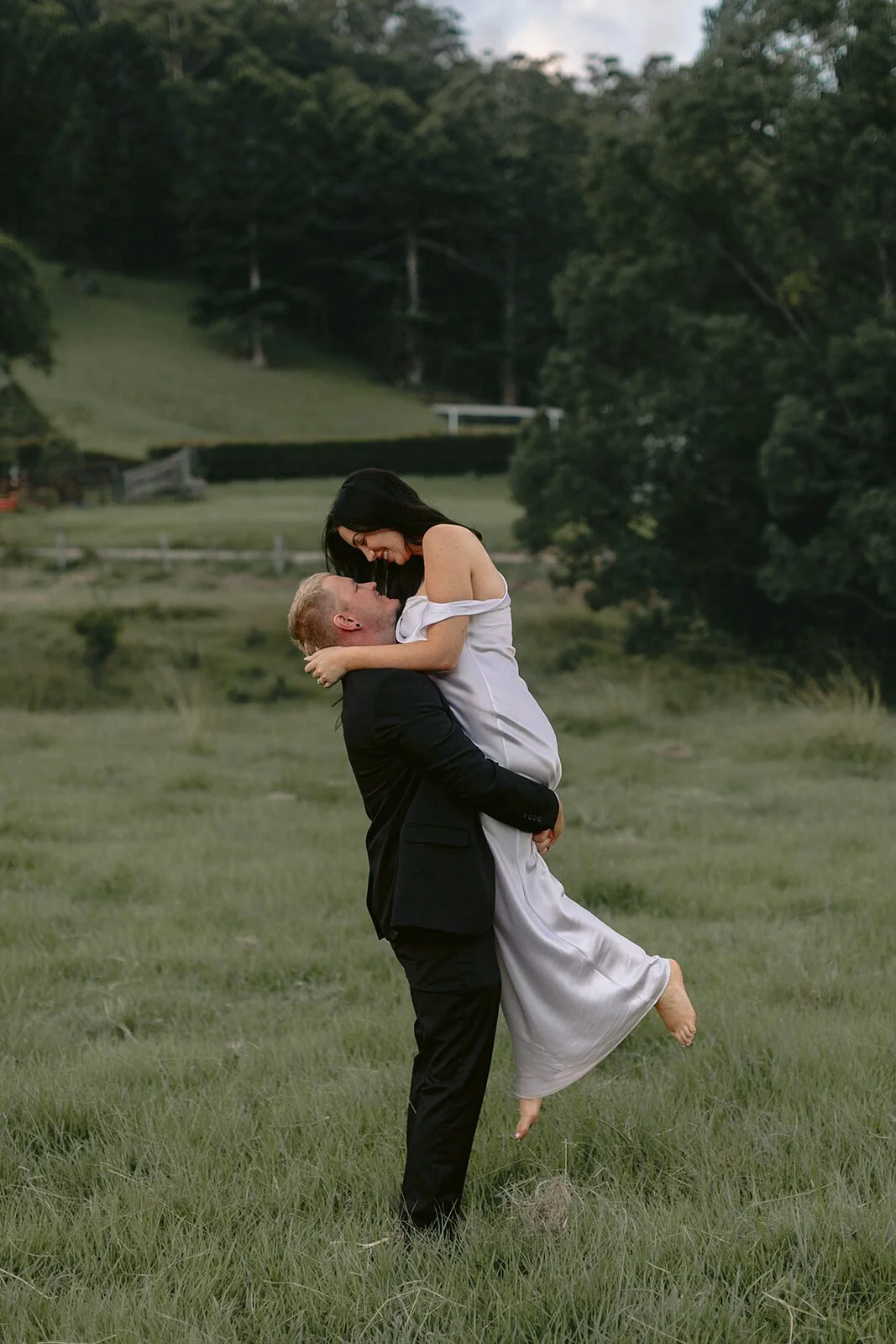Groom lifting the bride in the long grass, Kobi and Darren's elopement at Butterfly Lane, Byron Bay hinterland