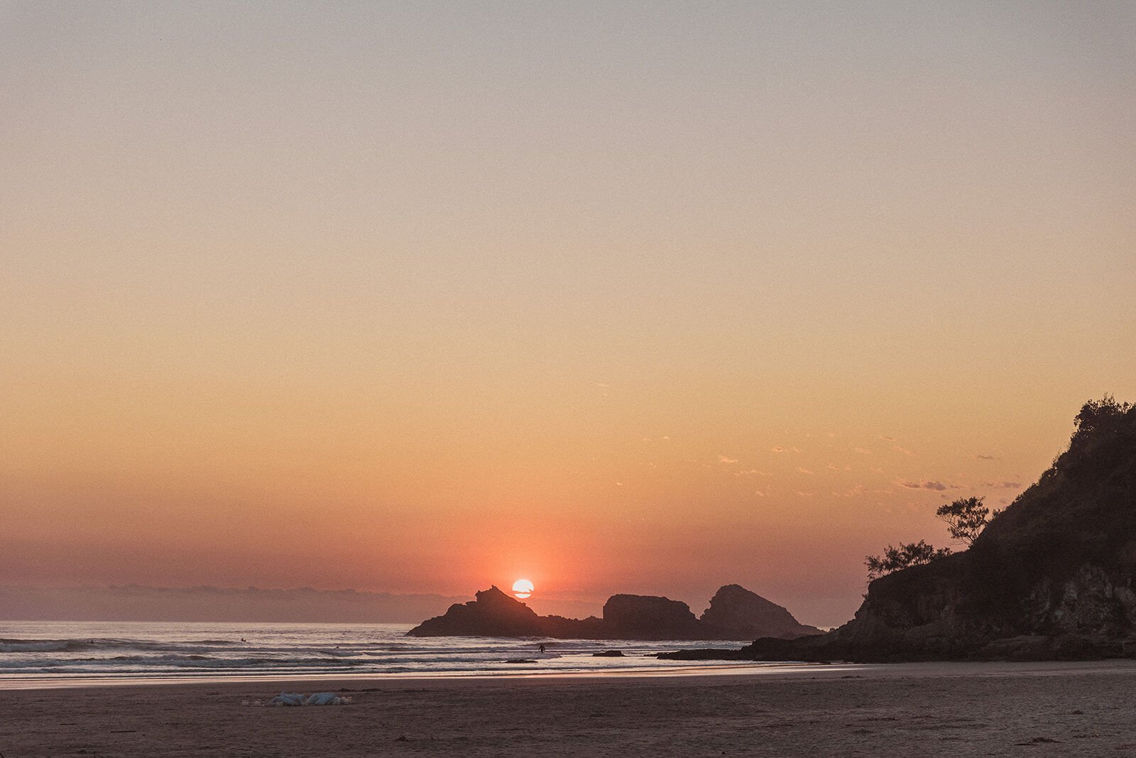 Sunrise glowing over the sea beside the rocky Broken Head headland, Charlie and Hannah's sunrise marriage proposal at Broken Head Beach, Byron Bay