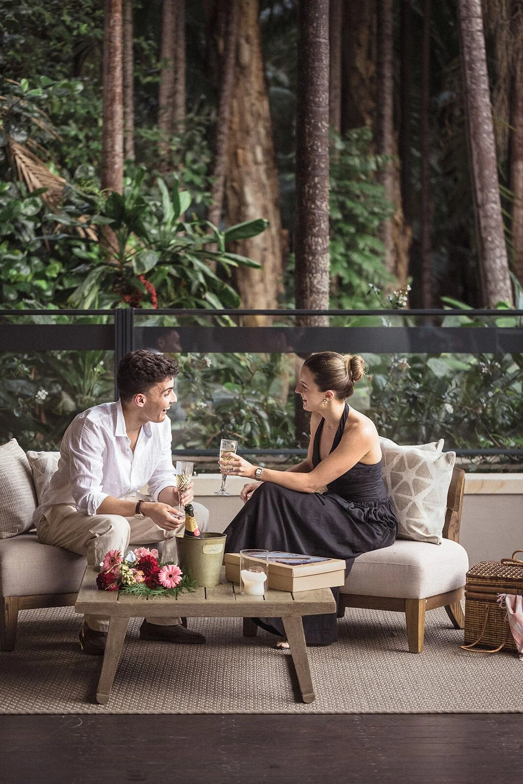 Wide view of the couple celebrating on the lounge in the rainforest, Ben and Chloe's marriage proposal in Byron Bay