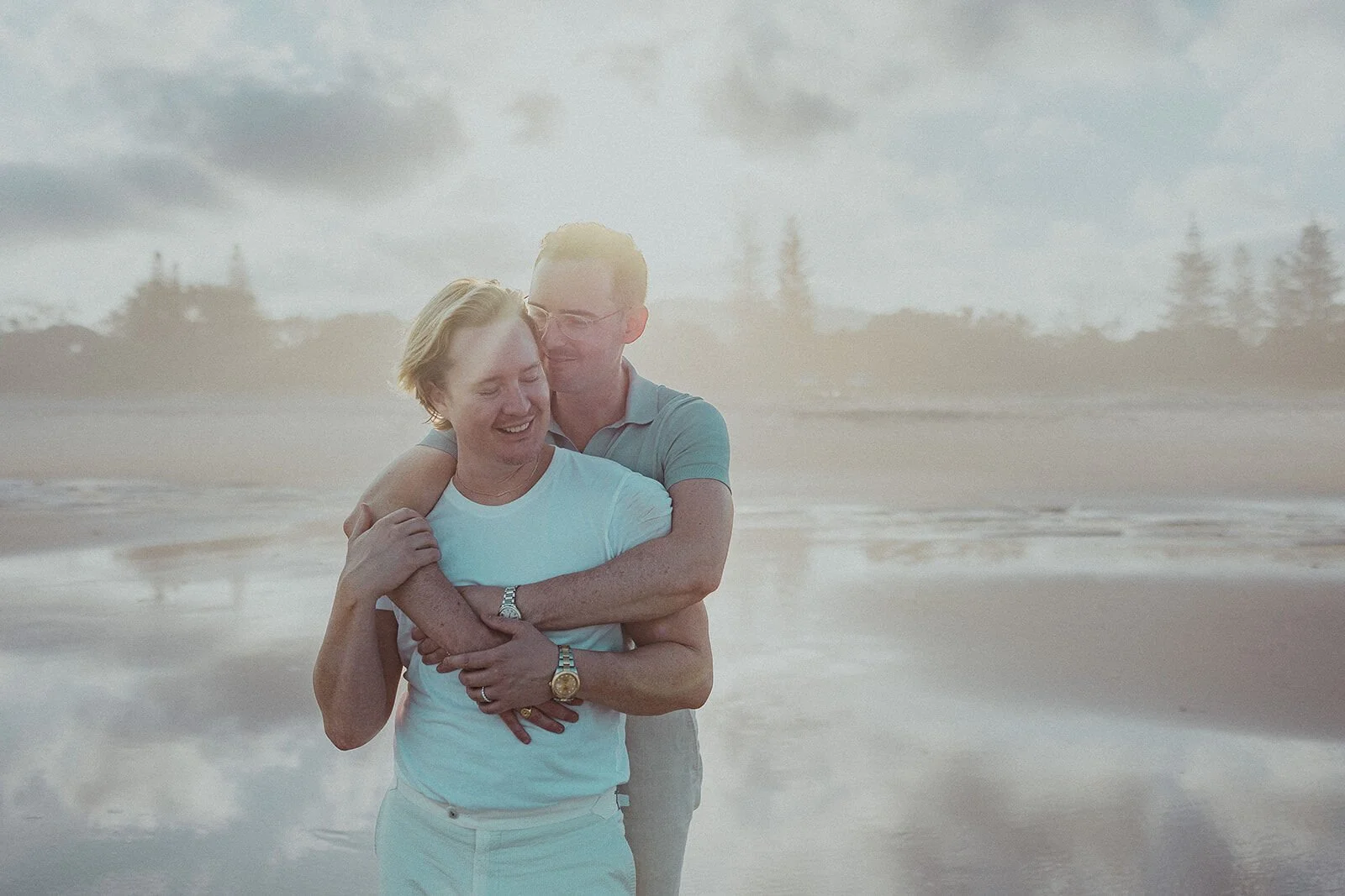 Couple hugging and laughing at the shoreline, Byron and Luke's marriage proposal at Cabarita Beach, Northern Rivers
