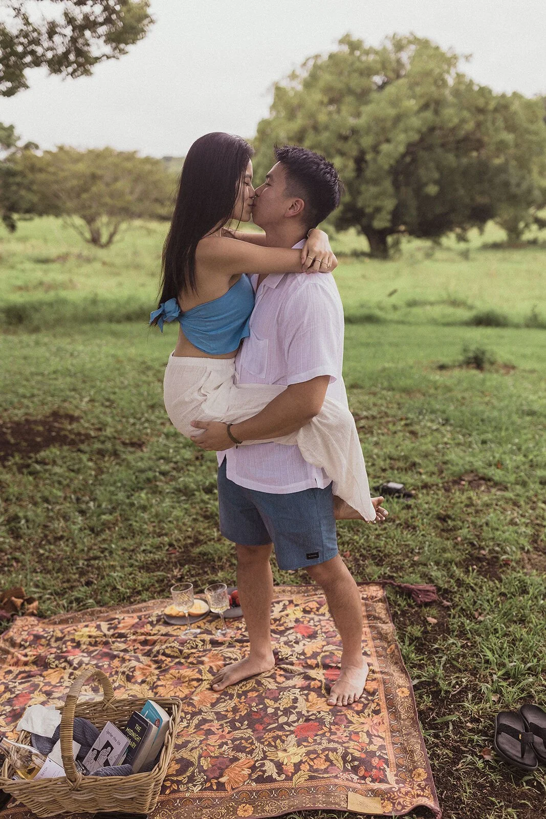 Couple kissing as he lifts her above the picnic rug, Darien and Jacqui's picnic marriage proposal at Heartwood Farm, Byron Bay hinterland