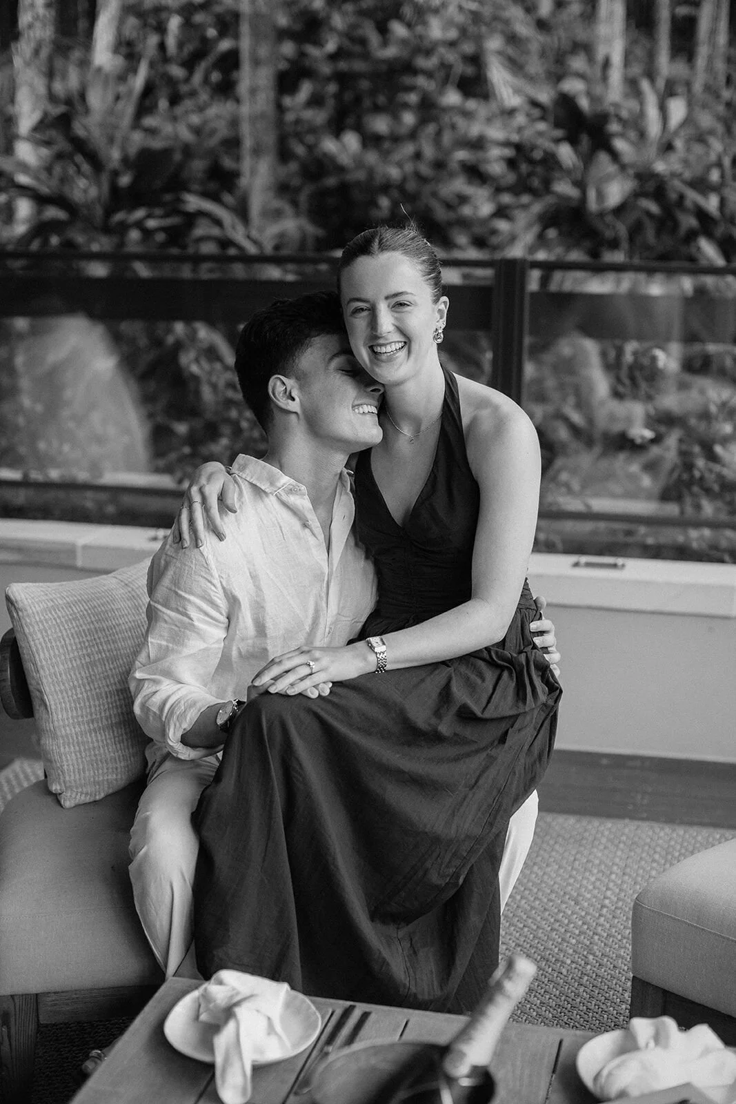 Black and white of the couple laughing together on the lounge, Ben and Chloe's marriage proposal in Byron Bay