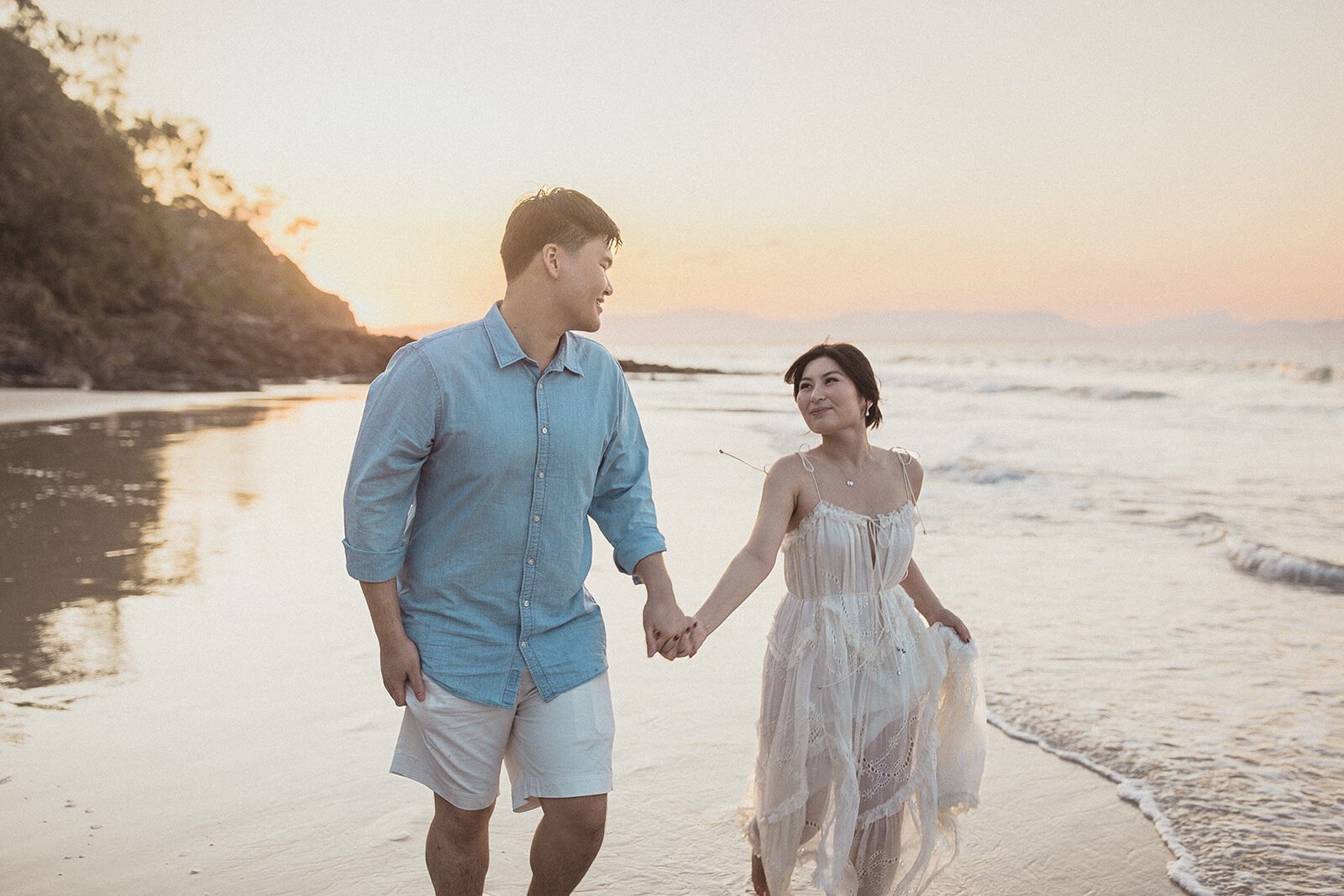 Couple holding hands and walking along the shoreline, Maggie and William's pre-wedding photos in Byron Bay