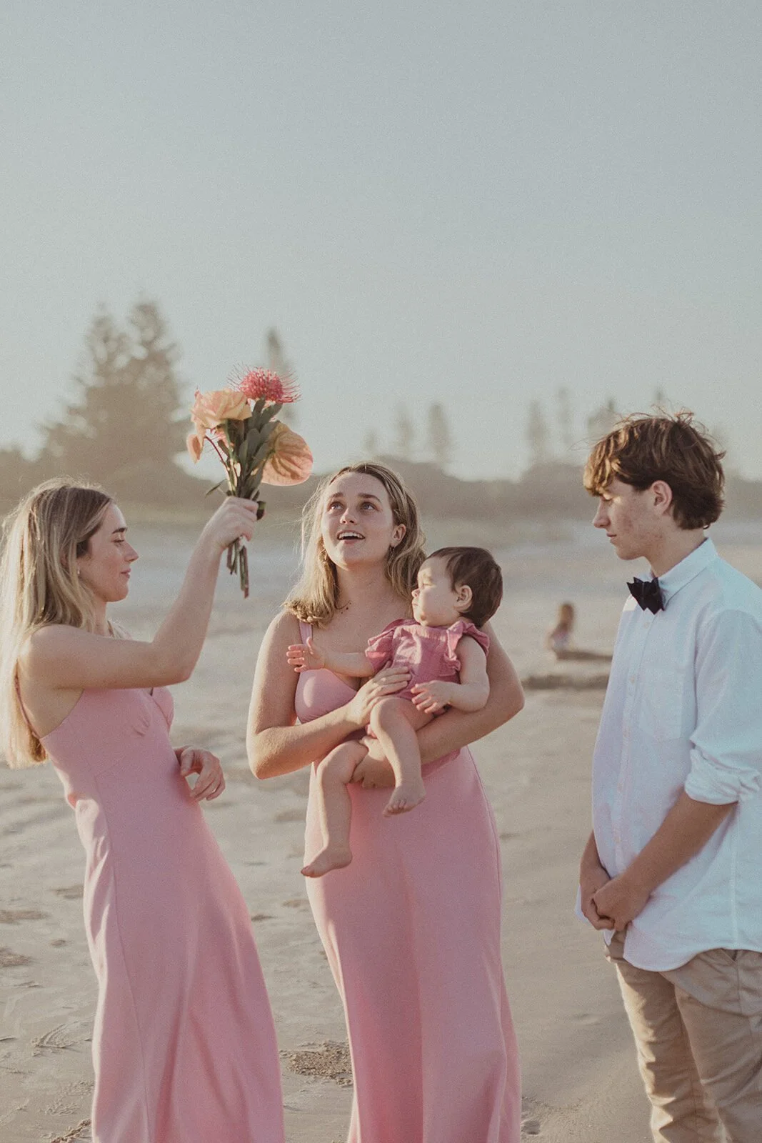 Two young women in pink dresses with the baby and a teenage boy, Maritess and Mark's elopement at Lennox Head