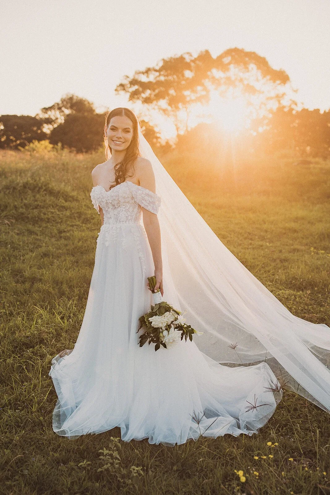 Bride holding her bouquet in front of the setting sun, Steph and William's wedding at Earth House, Byron Bay