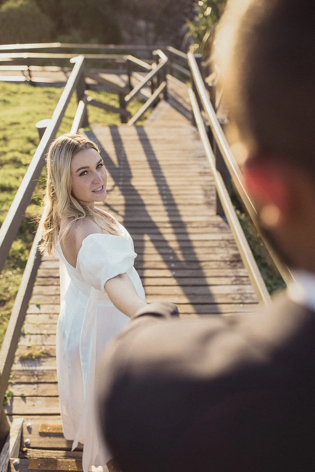 Bride looking back while holding the groom's hand on the wooden steps, Brittany and Mark's elopement at Cabarita Beach, Northern Rivers