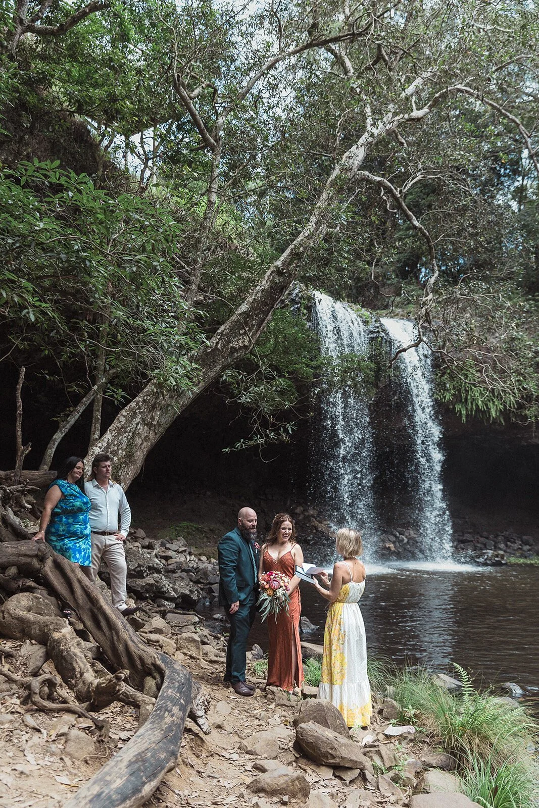 Wide ceremony at Killen Falls with guests watching from a log, Sara and Graeme's elopement, Northern Rivers