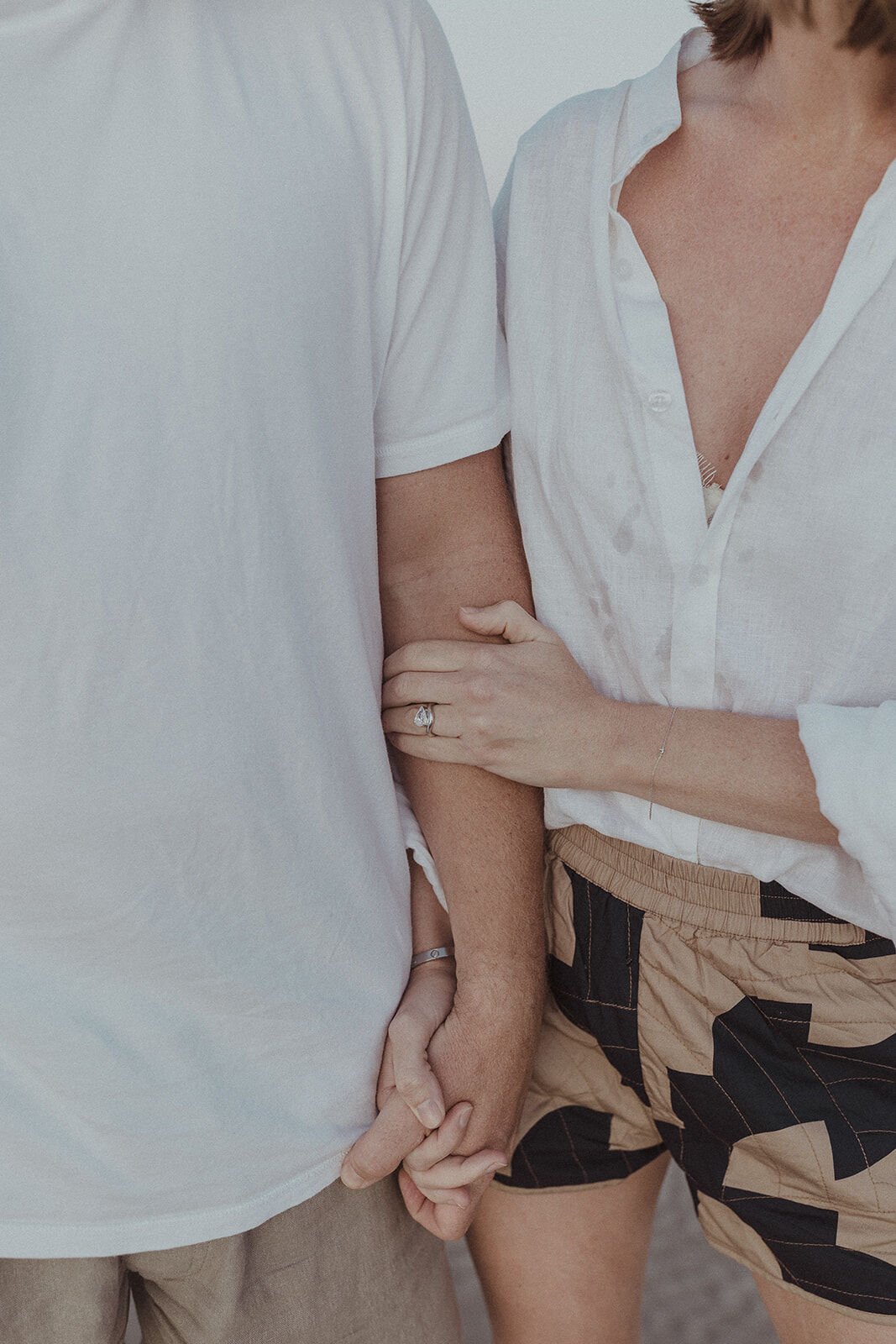 Close up of the couple's hands clasped together, Jamie and Jessica's beach marriage proposal at Belongil Beach, Byron Bay