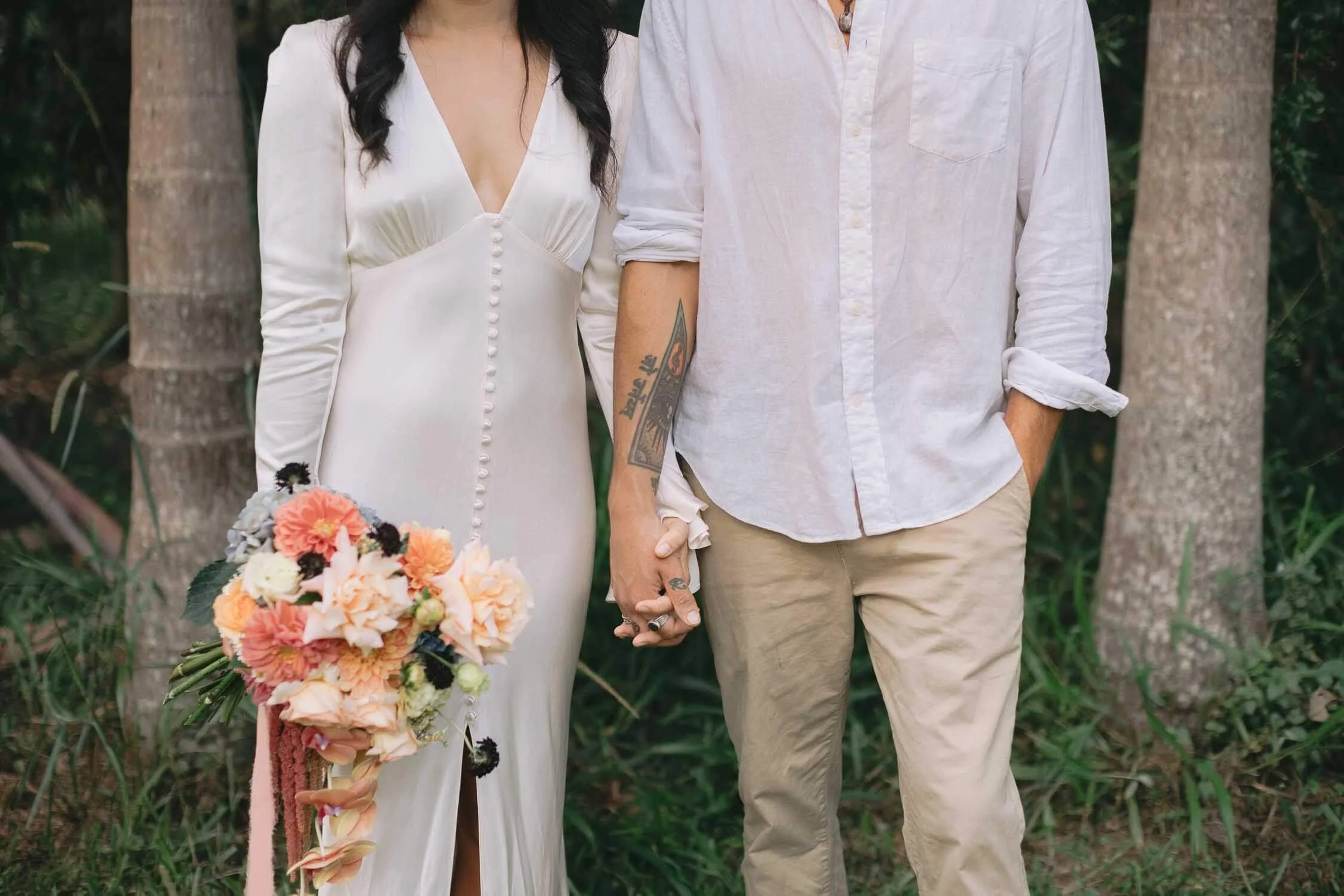 Bride and groom holding hands on their Byron hinterland elopement, bouquet in hand