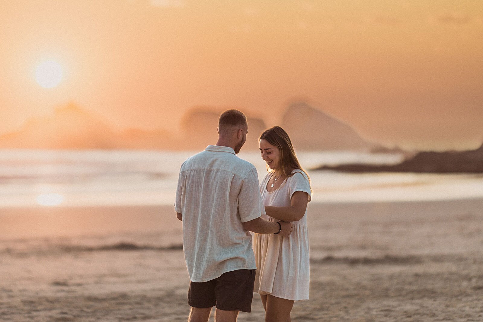 Couple looking at the engagement ring in the golden light, Charlie and Hannah's sunrise marriage proposal at Broken Head Beach, Byron Bay
