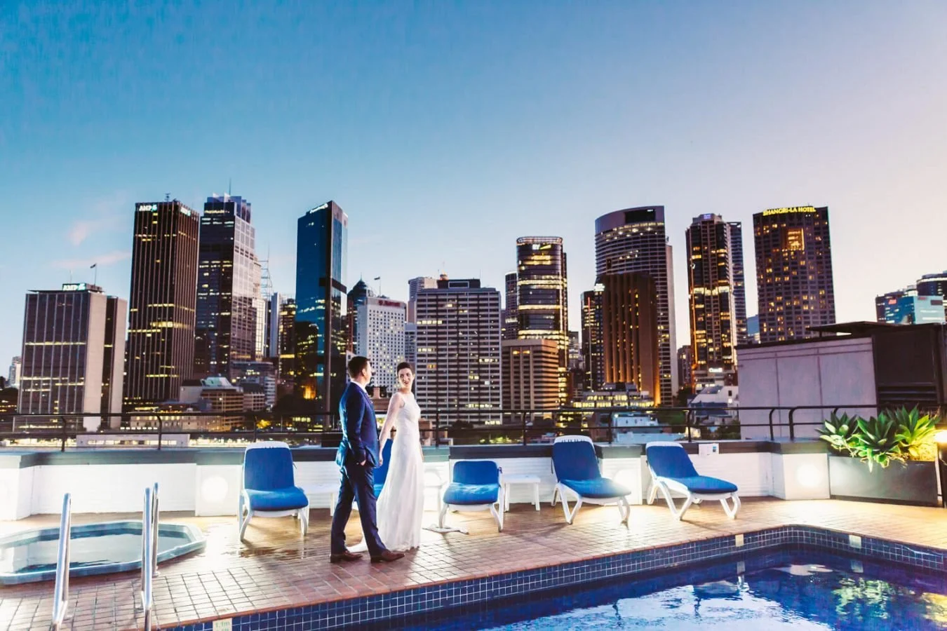 Couple on a rooftop terrace with the Sydney city skyline behind at dusk