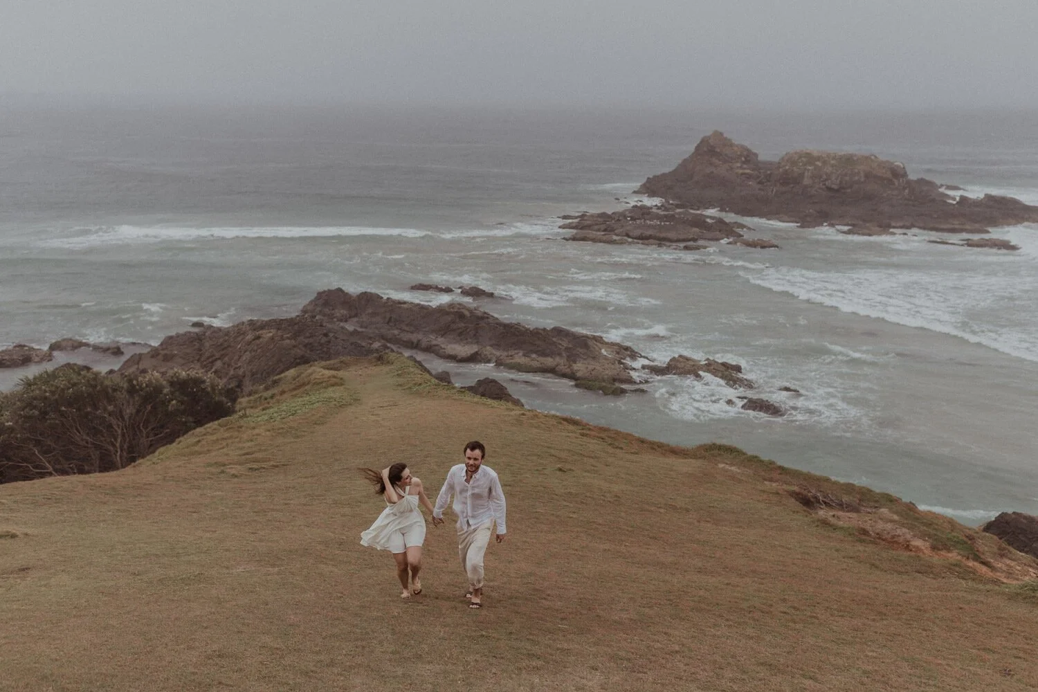 Couple running on the headland, Yoanne and Elisa's rainy elopement at Broken Head, Byron Bay