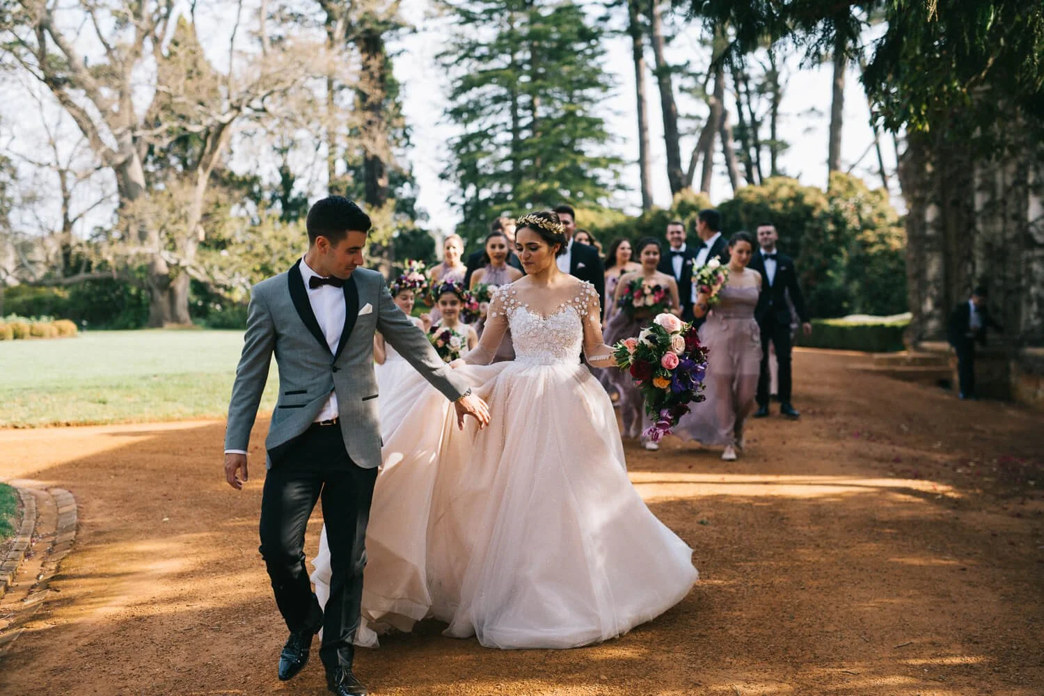 Bride and groom walking down the gravel drive with their guests at Bendooley Estate