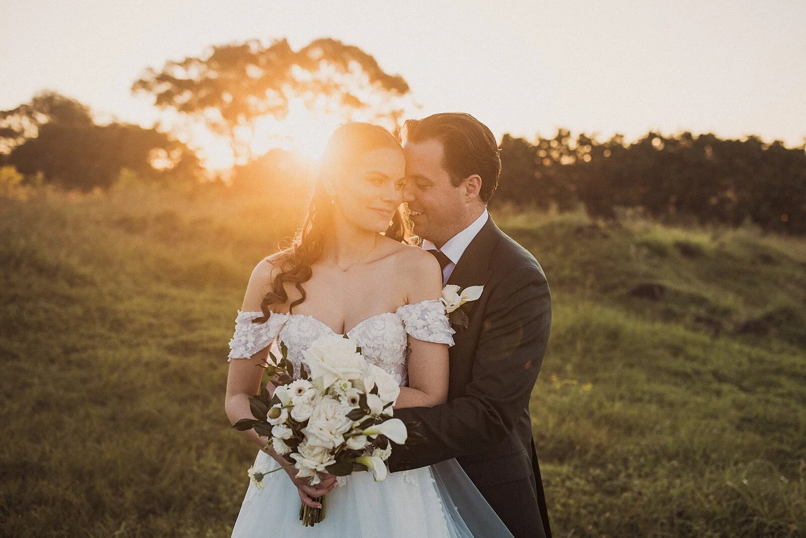 Bride and groom embracing in golden sunset light at Earth House, Byron Bay wedding photographer