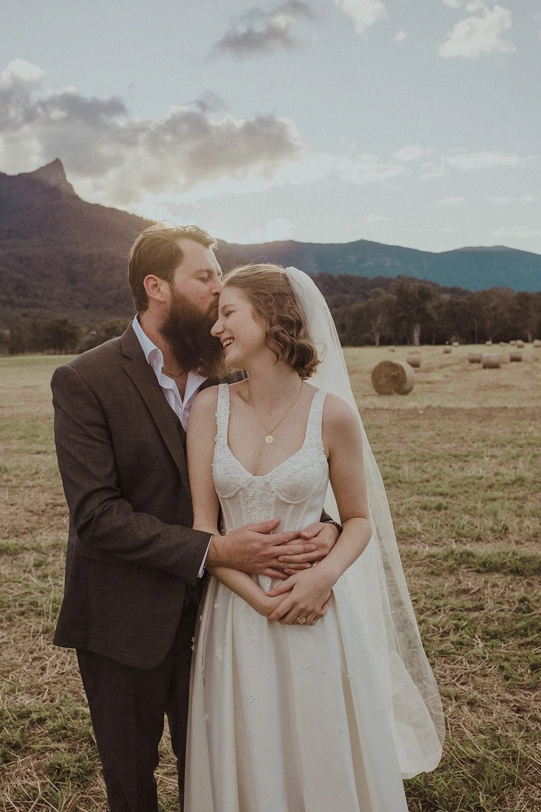 Groom kissing the bride's cheek in the field, Sam and Tom's elopement at Highfield Farm, Northern Rivers