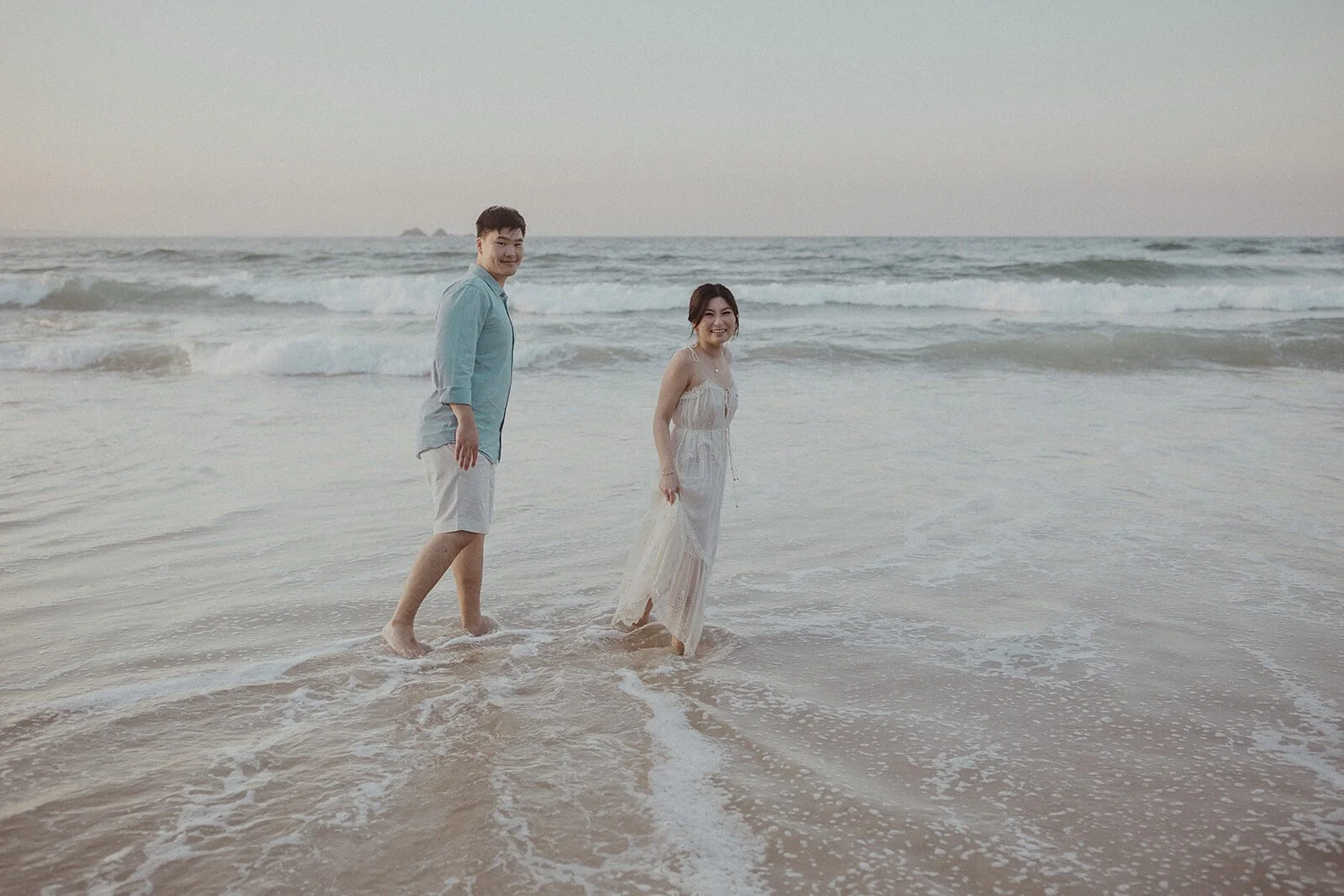 Couple walking toward each other in the surf, Maggie and William's pre-wedding photos in Byron Bay