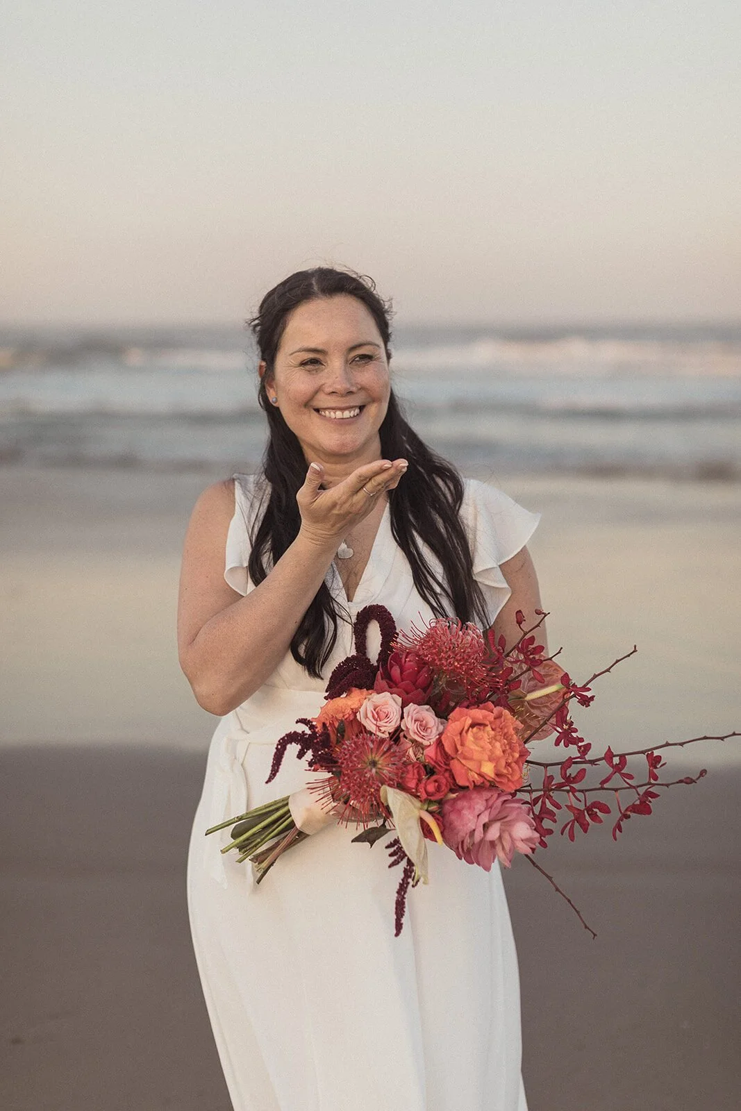 Bride blowing a kiss with her bouquet, Maritess and Mark's elopement at Lennox Head