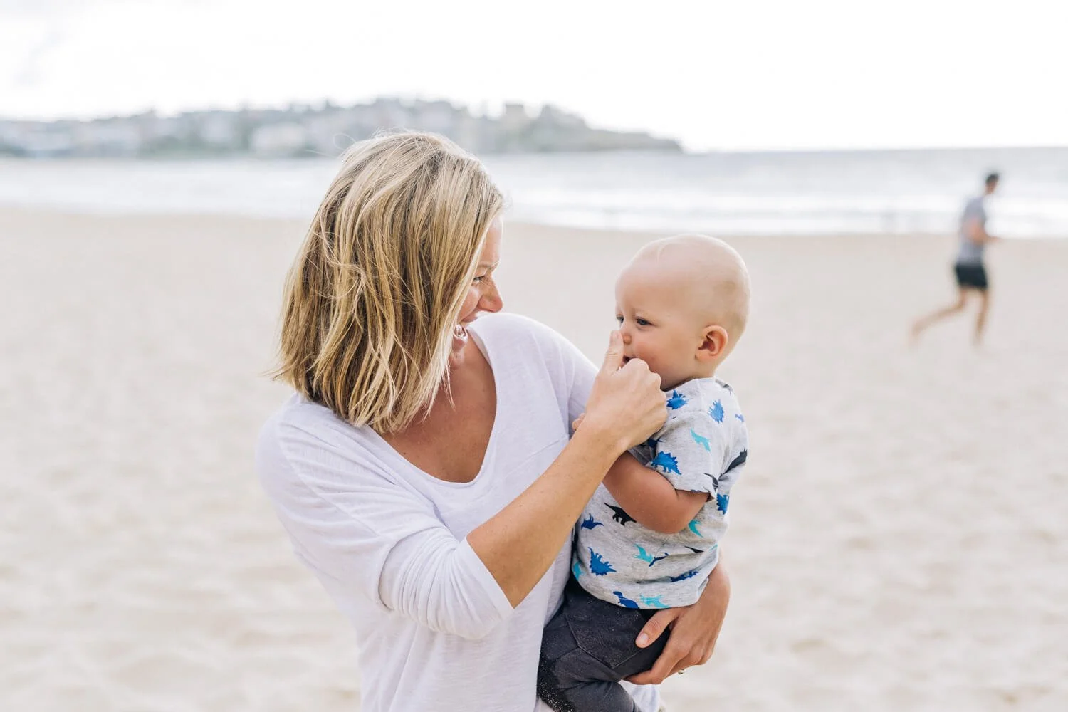 Mother laughing with her baby son on Bondi Beach