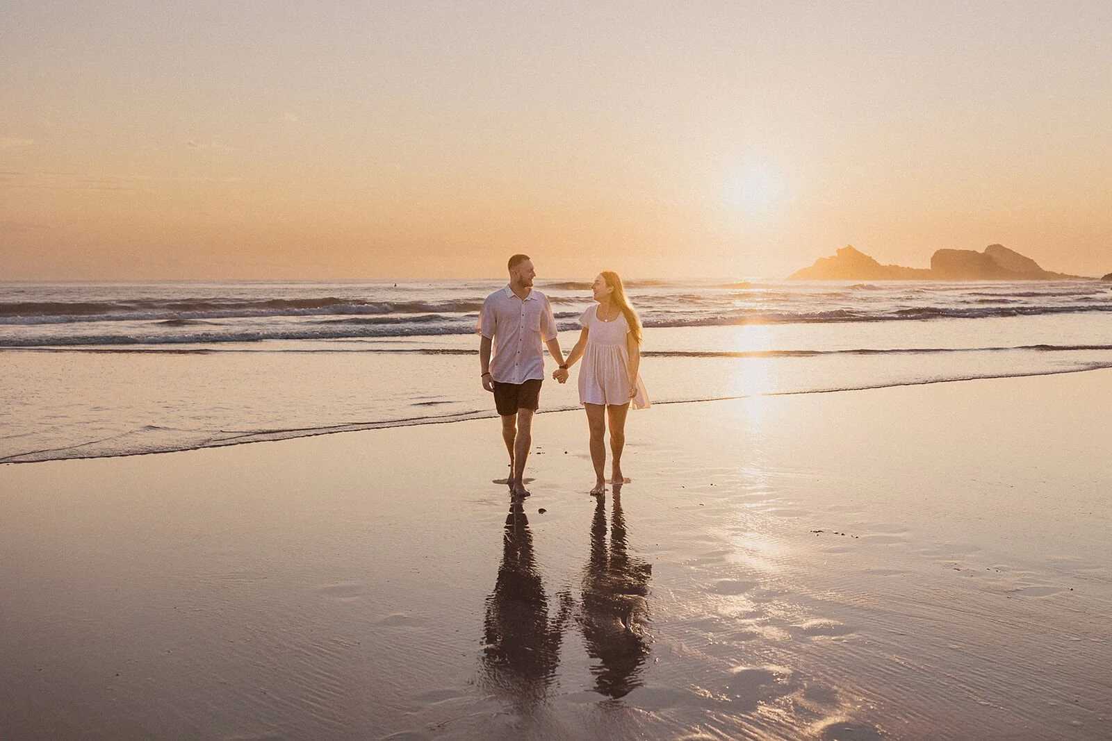 Couple walking hand in hand along the shoreline at sunrise, Charlie and Hannah's sunrise marriage proposal at Broken Head Beach, Byron Bay