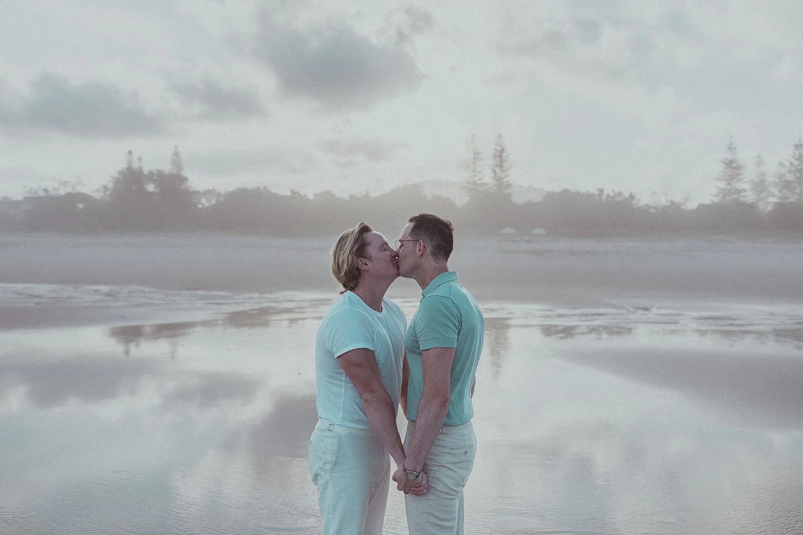Couple kissing at the shoreline with reflections in the wet sand, Byron and Luke's marriage proposal at Cabarita Beach, Northern Rivers