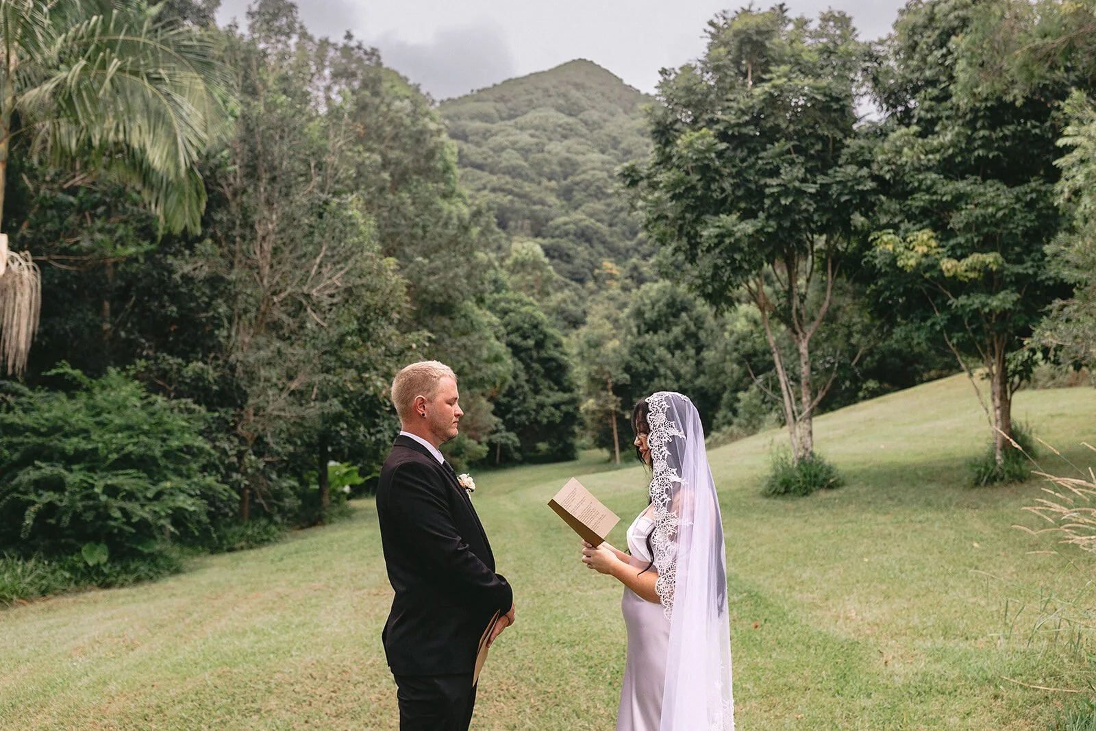 Groom reading to the bride on the lawn, Kobi and Darren's elopement at Butterfly Lane, Byron Bay hinterland