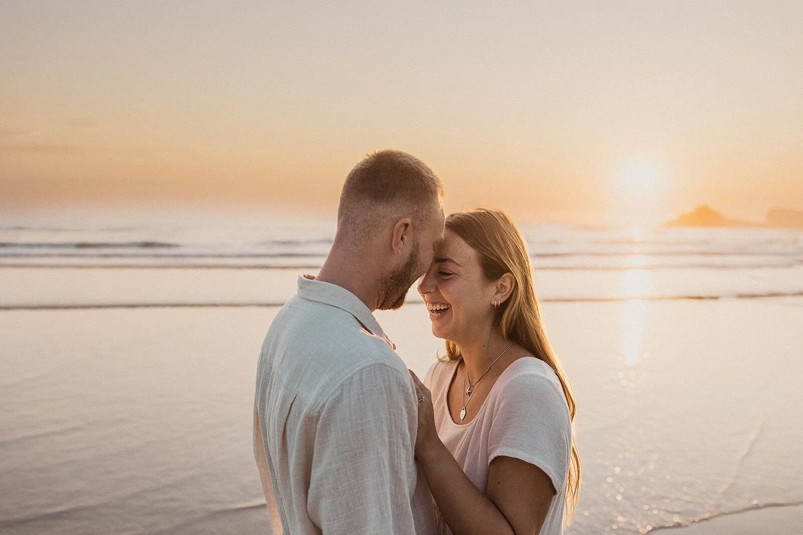 Couple nose to nose and laughing at sunrise, Charlie and Hannah's sunrise marriage proposal at Broken Head Beach, Byron Bay