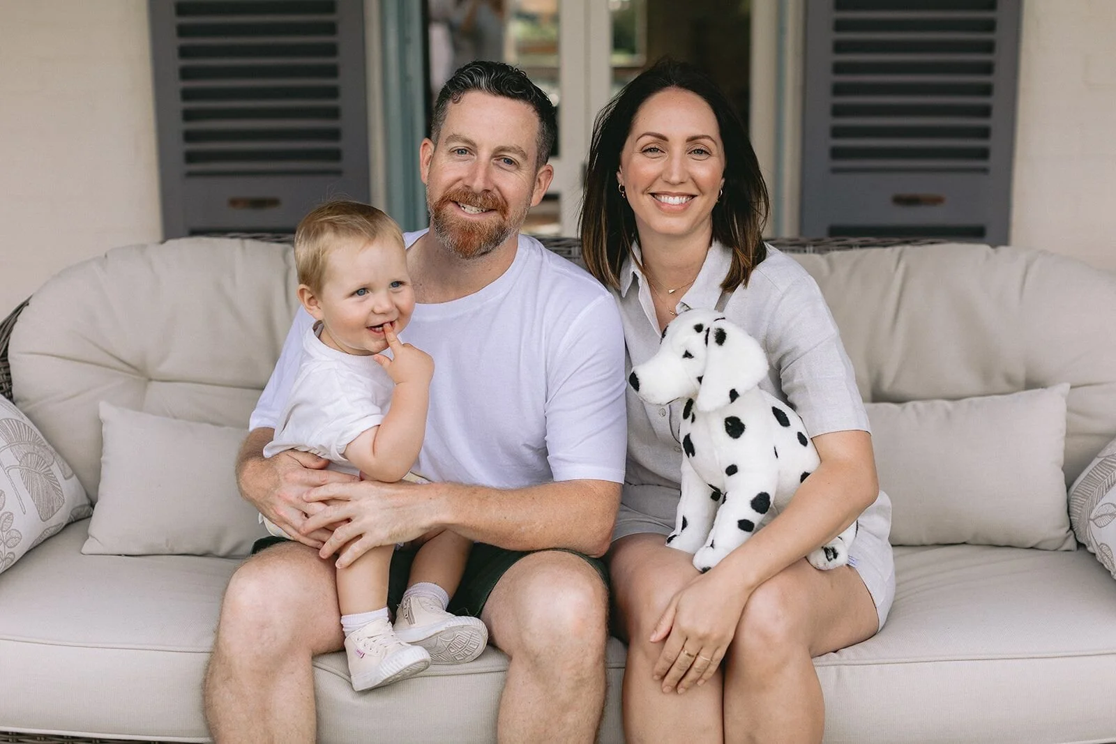 Young parents with their toddler son and a toy dalmatian, sitting on a verandah couch
