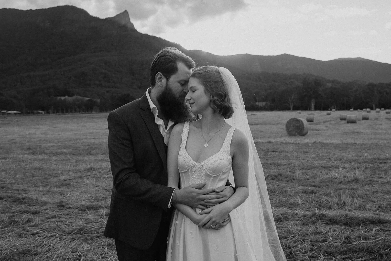 Black and white of the couple embracing in the field, Sam and Tom's elopement at Highfield Farm, Northern Rivers