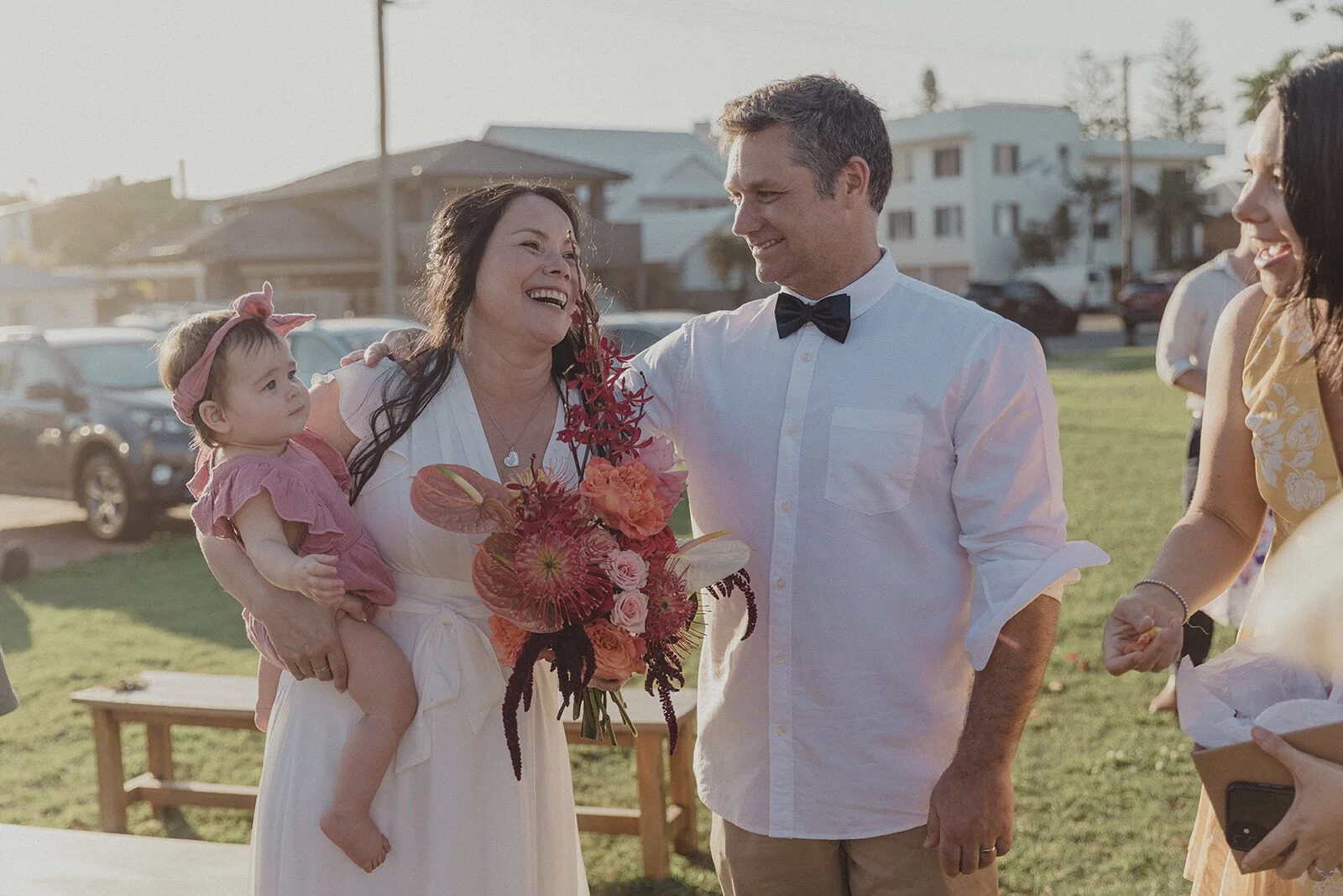 Bride carrying a baby beside the groom at the ceremony, Maritess and Mark's elopement at Lennox Head