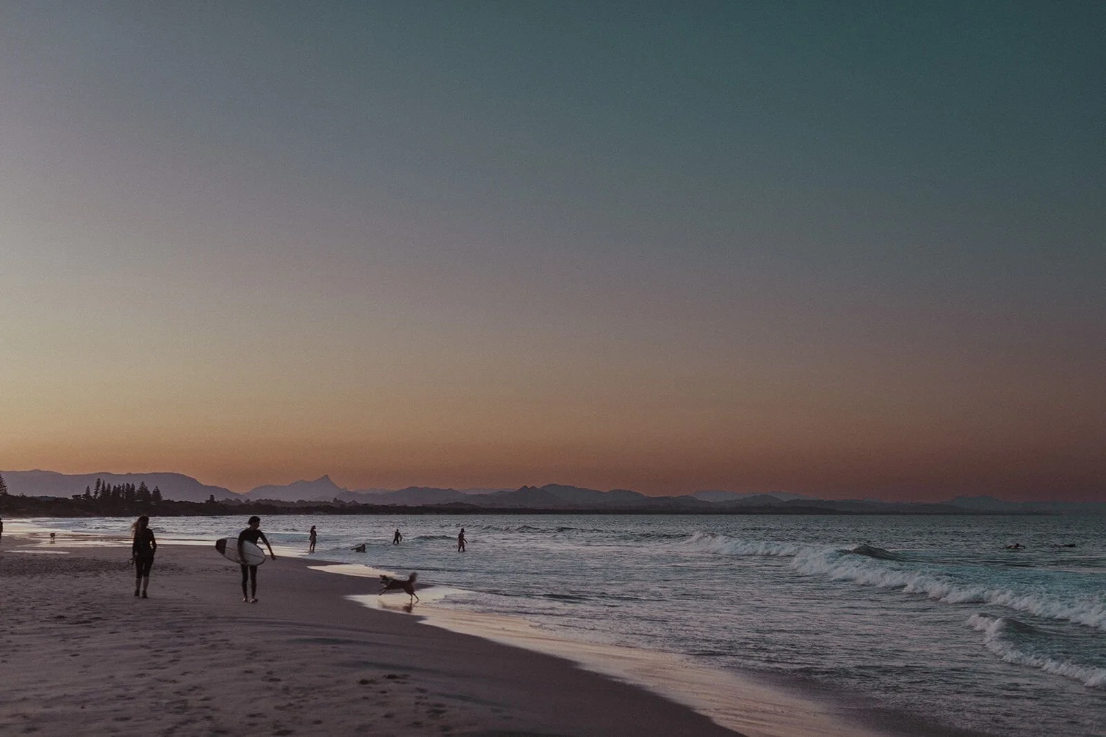 Dusk sky over Belongil Beach with surfers and distant mountains, Jamie and Jessica's beach marriage proposal at Belongil Beach, Byron Bay
