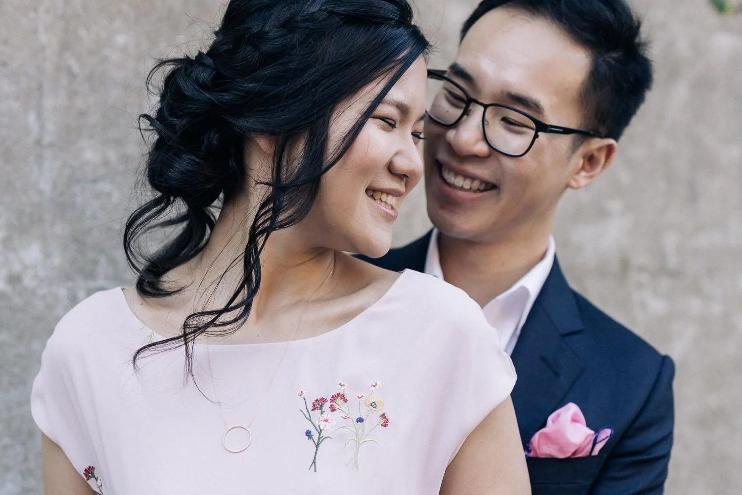 Couple laughing cheek to cheek against a sandstone wall in The Rocks, Sydney