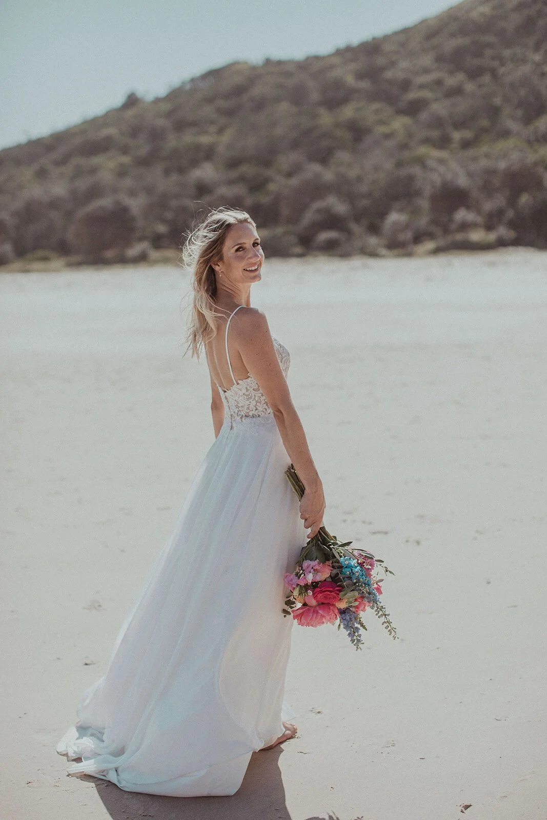 Bride looking over her shoulder on the beach, Eliza and Greg's elopement at Broken Head, Byron Bay