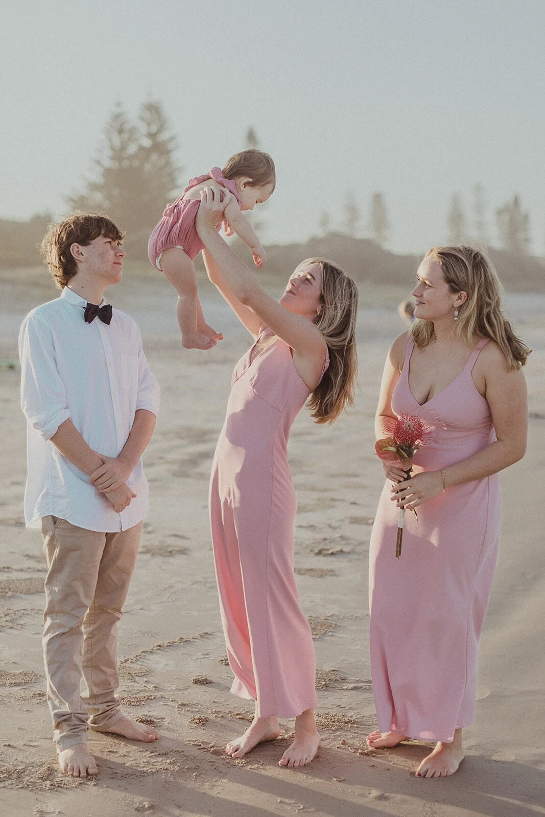 Young woman lifting the baby in the air on the beach, Maritess and Mark's elopement at Lennox Head