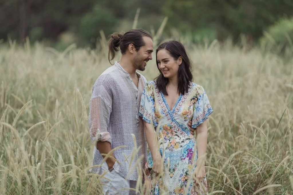 Couple smiling at each other in long golden grass in Centennial Park, Sydney