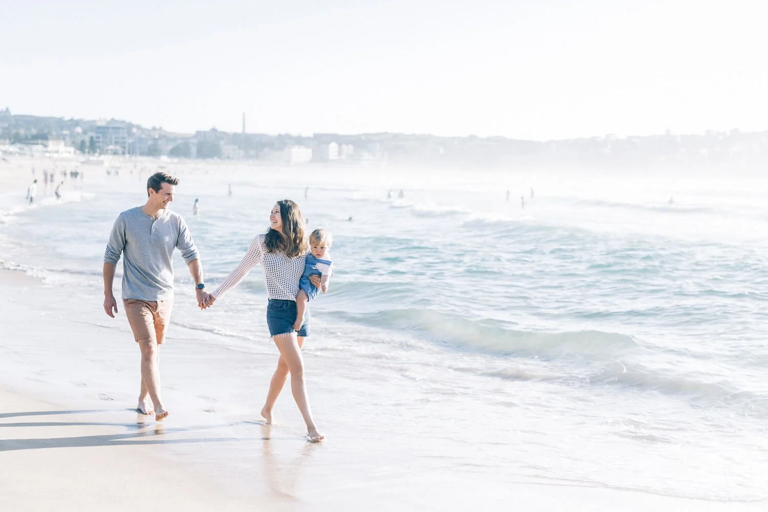 Family walking hand in hand along Bondi Beach at sunrise
