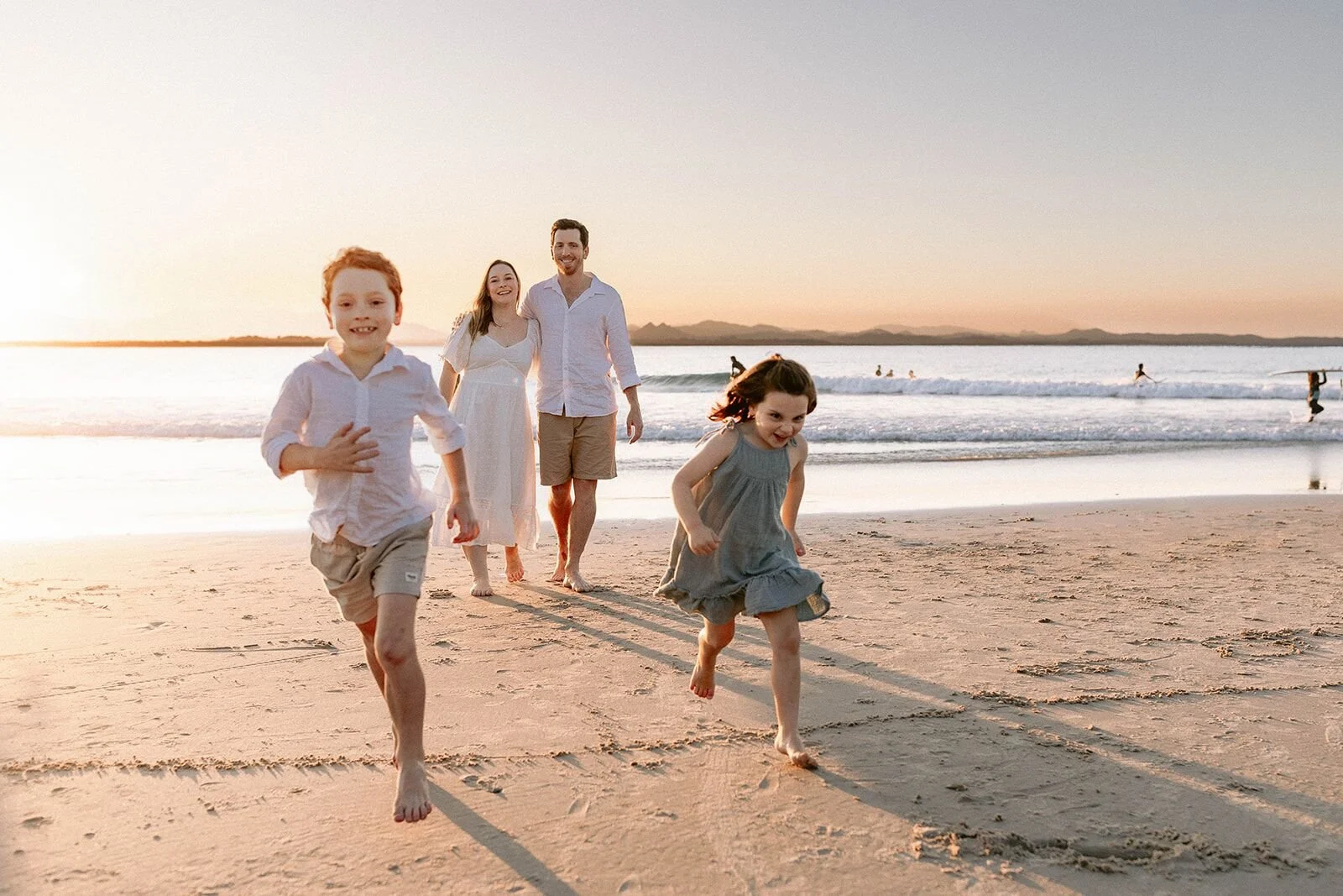 Children racing ahead of their parents along the golden sand, laughing