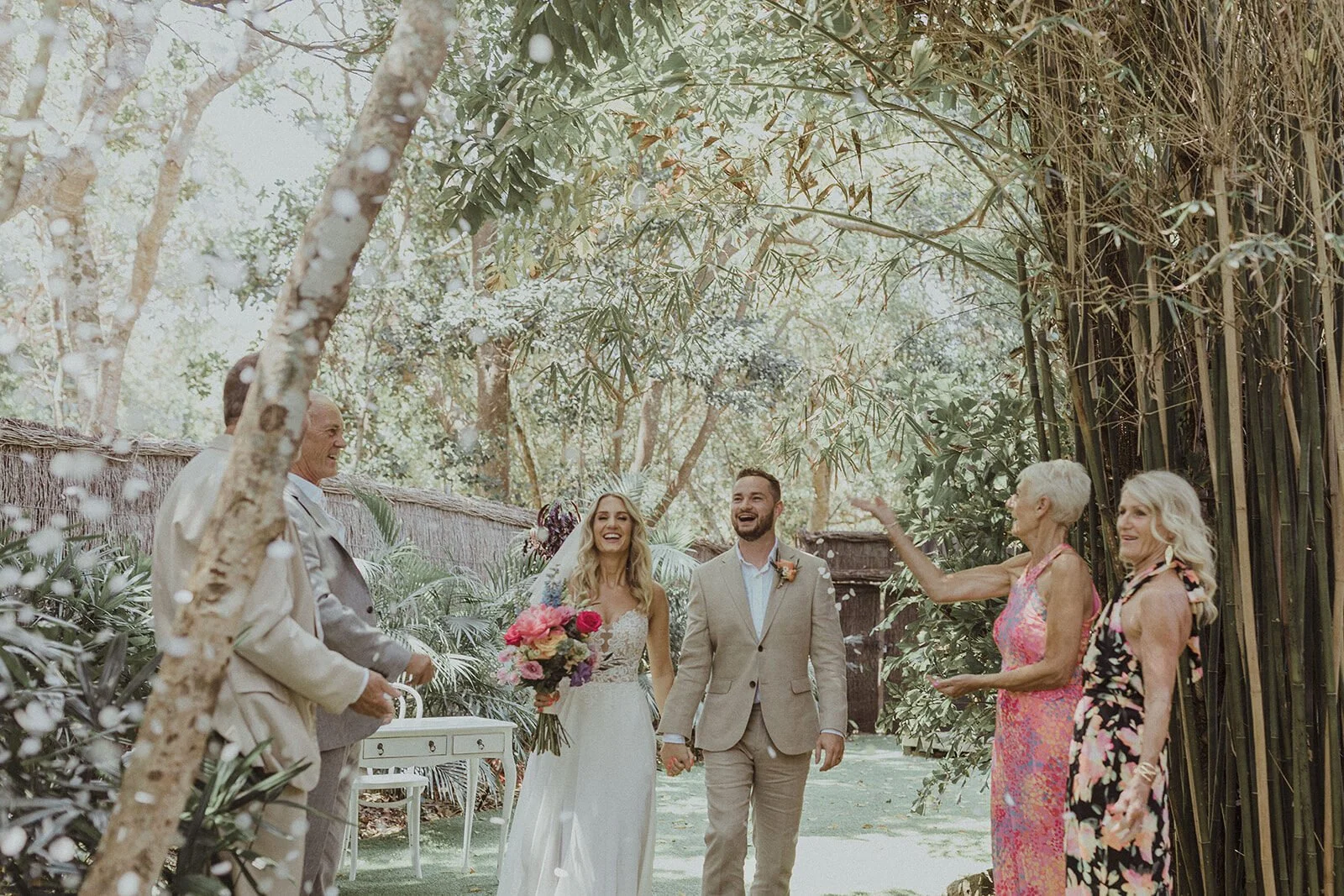 Couple walking with guests cheering in the bamboo garden, Eliza and Greg's elopement at Broken Head, Byron Bay