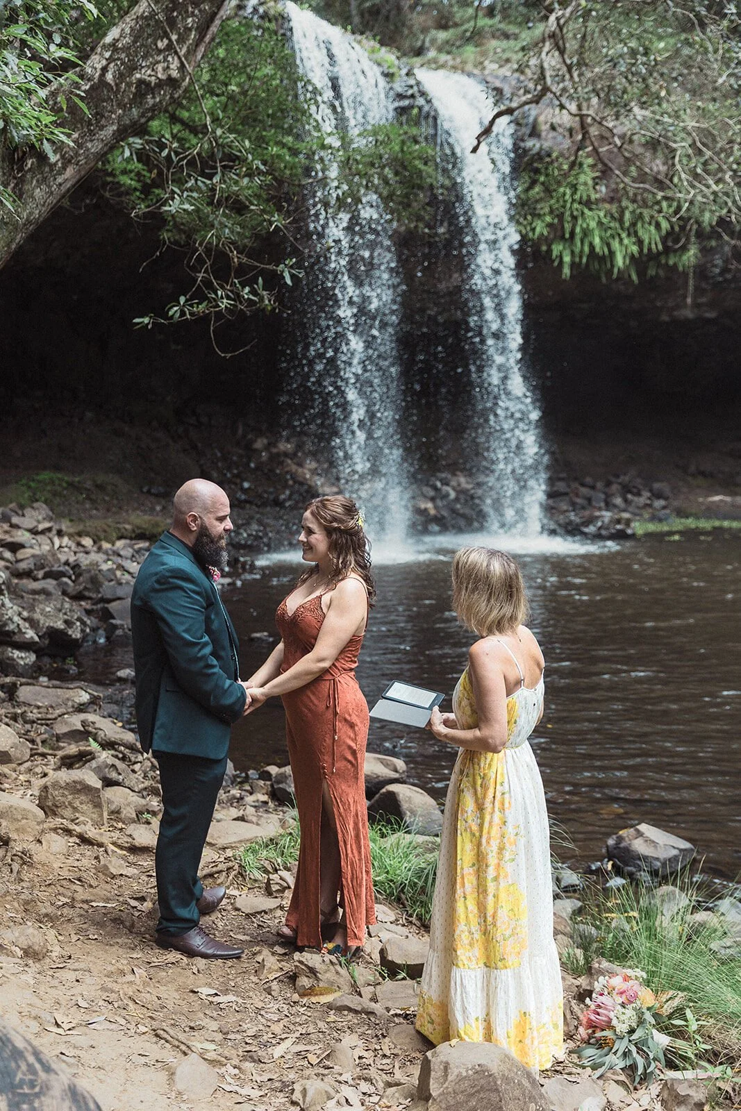 Couple exchanging vows with the celebrant at the waterfall pool, Sara and Graeme's elopement at Killen Falls, Northern Rivers