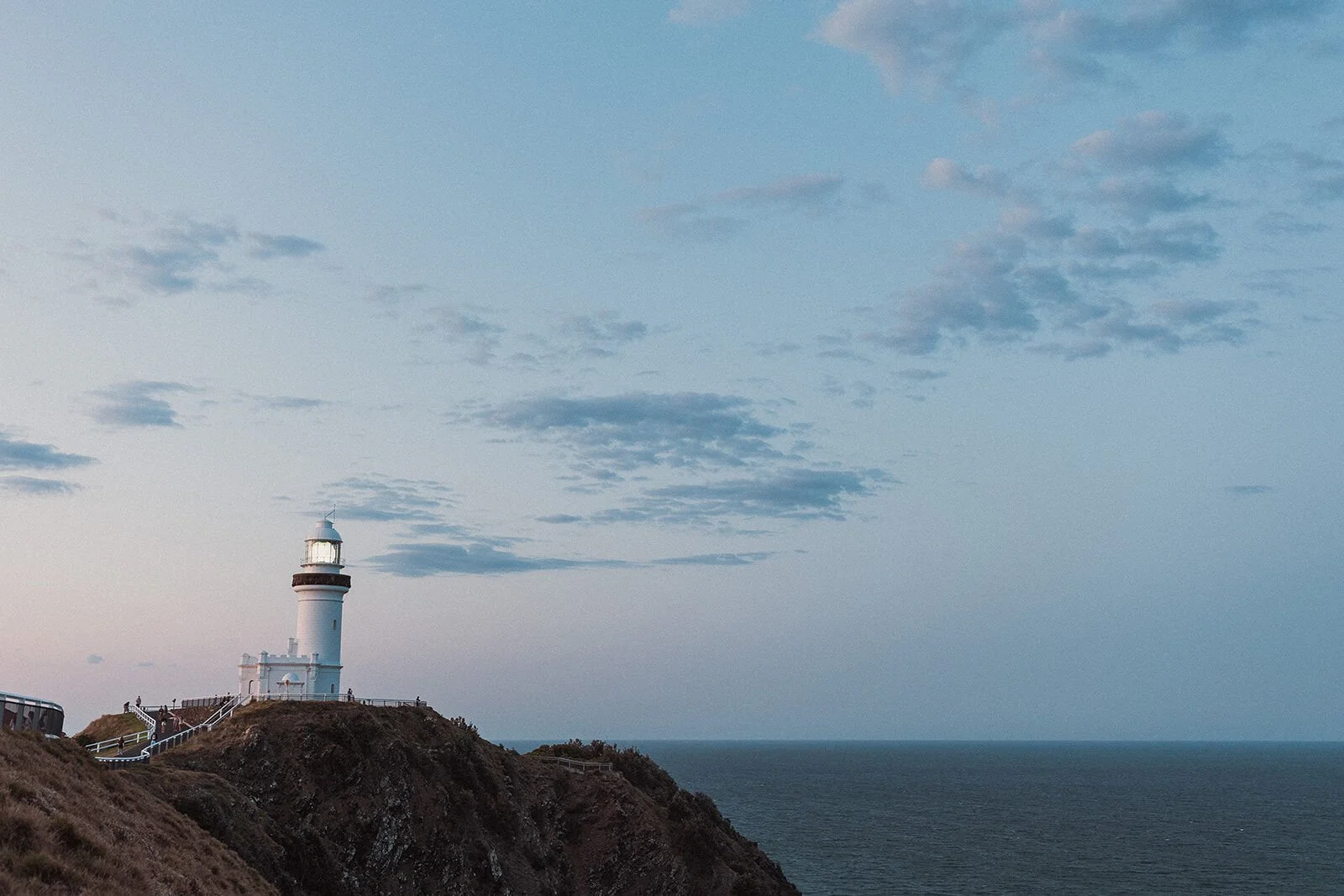 Cape Byron Lighthouse lit on the headland at dusk, Douglas and Ying's sunset marriage proposal at Cape Byron Lighthouse, Byron Bay