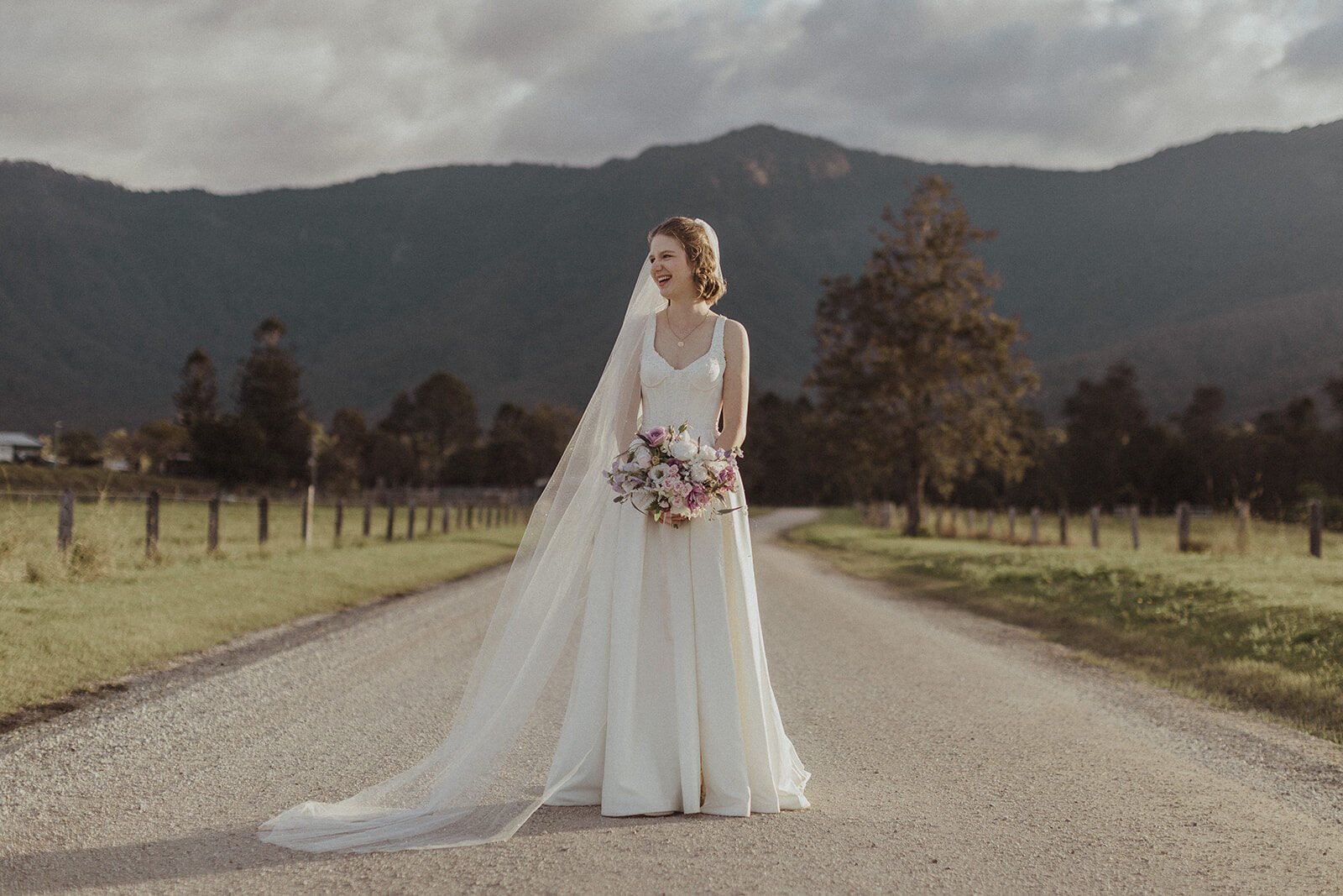 Bride with a long veil and bouquet on the road, Sam and Tom's elopement at Highfield Farm, Northern Rivers