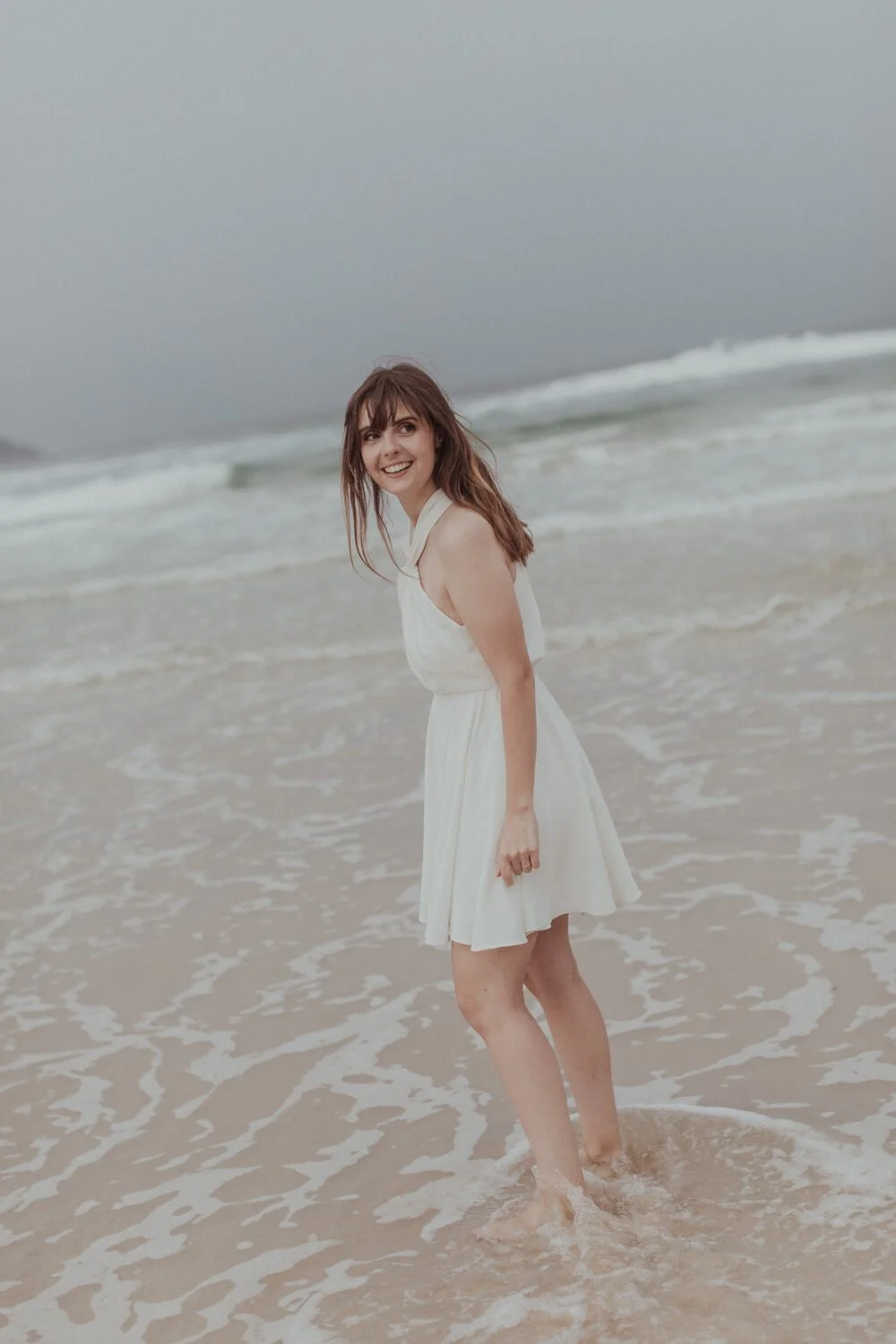 Bride laughing in the shallows, Yoanne and Elisa's rainy elopement at Broken Head, Byron Bay