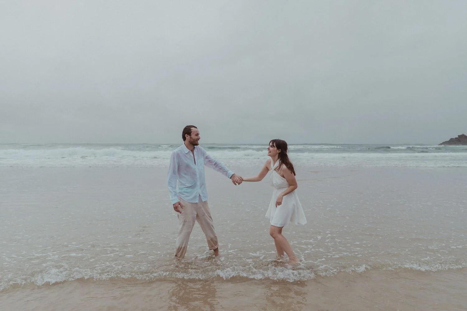 Couple holding hands in the shallows, Yoanne and Elisa's rainy elopement at Broken Head, Byron Bay