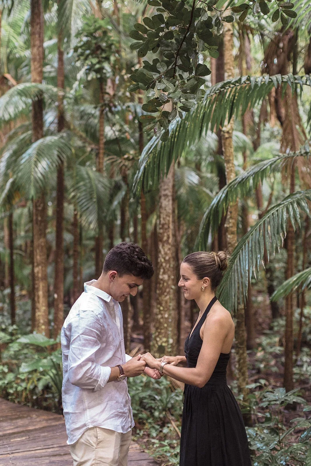 Man placing the ring on her finger on the forest boardwalk, Ben and Chloe's marriage proposal in Byron Bay