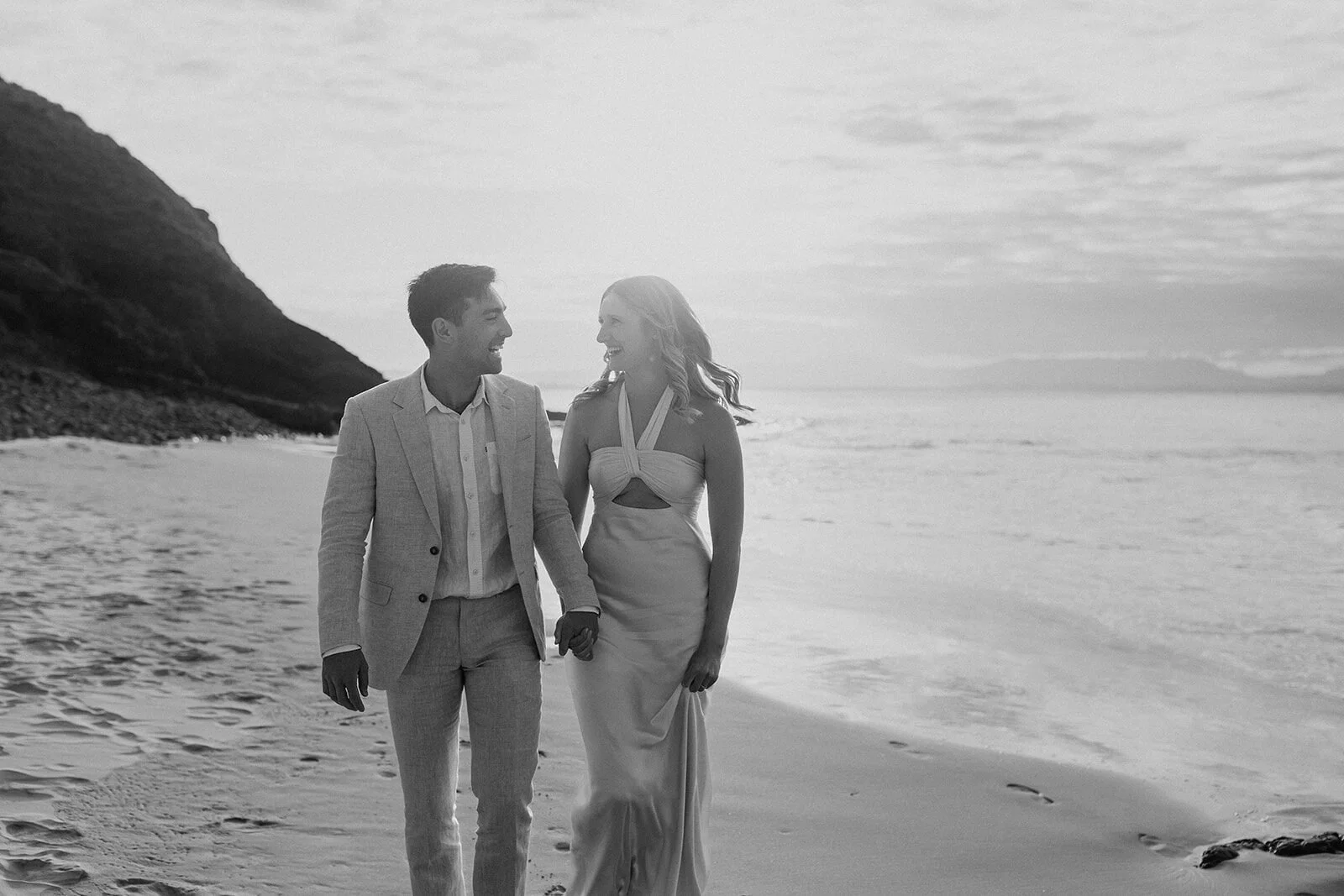 Black and white of the couple walking hand in hand along the shore, Abby and James' elopement at Little Wategos Beach, Byron Bay