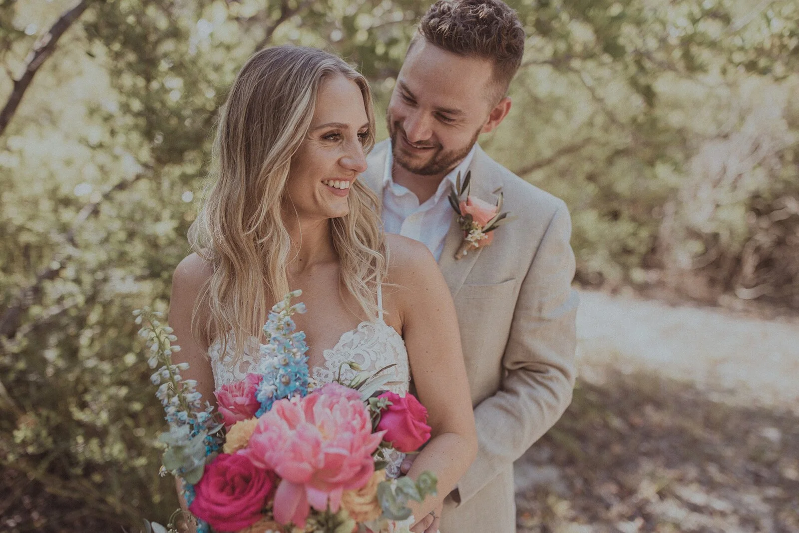 Couple laughing among coastal bush with a bright bouquet, Eliza and Greg's elopement at Broken Head, Byron Bay