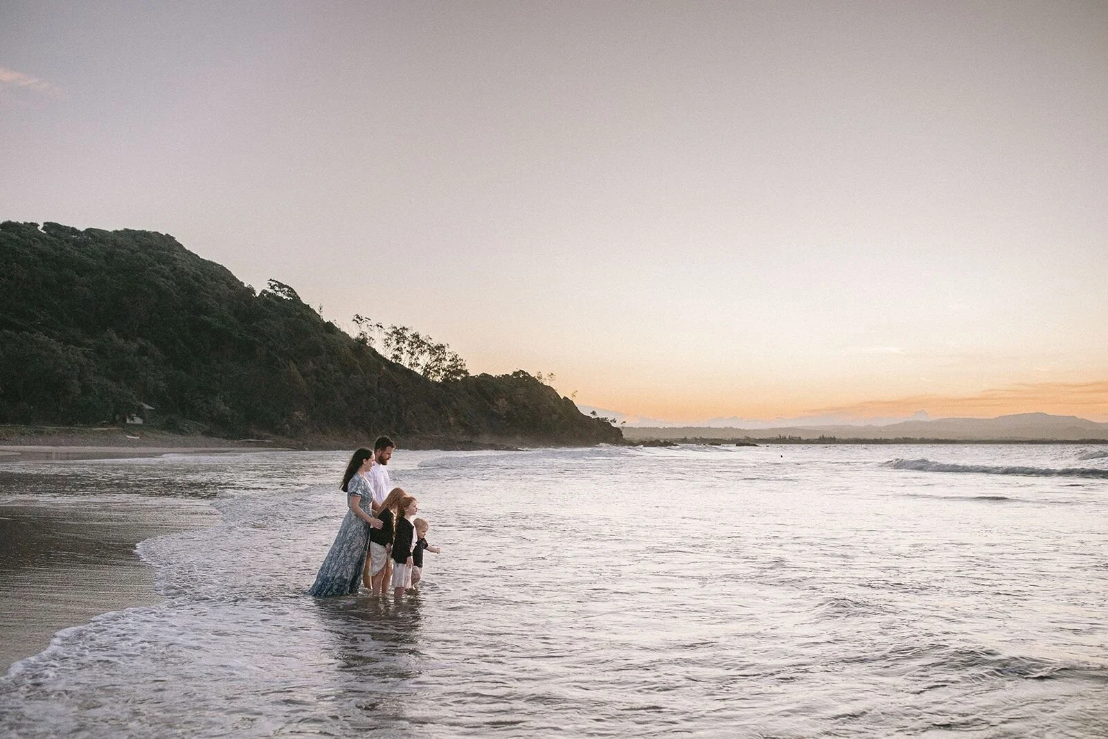 Family wading together in the shallows below the Wategos headland at dusk
