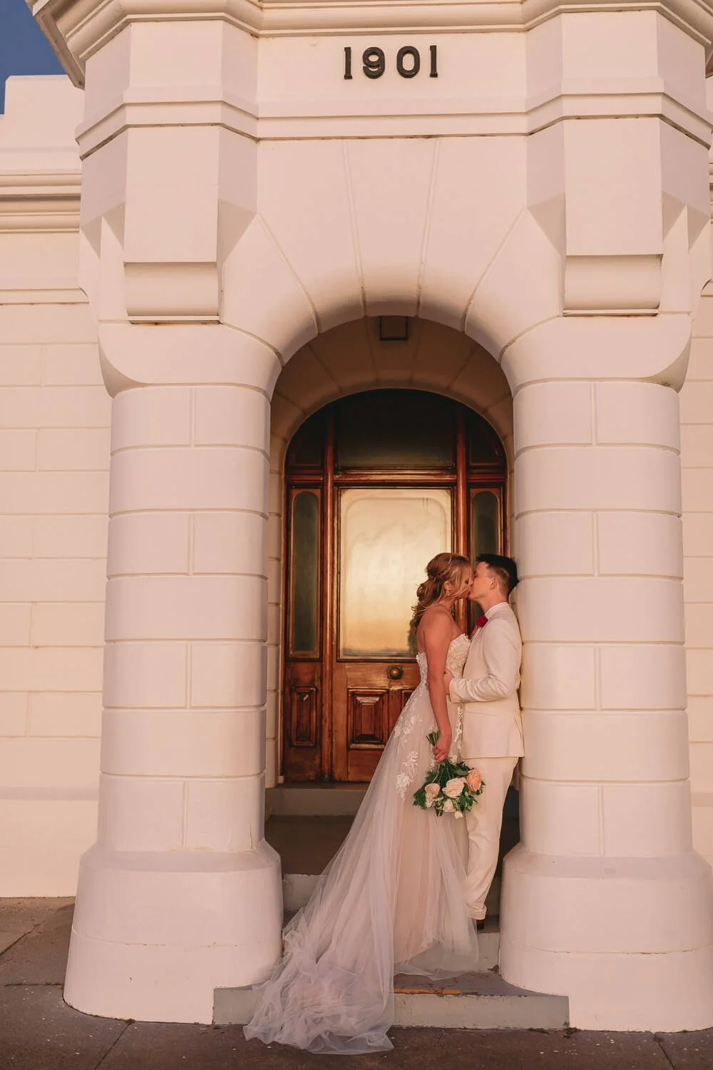 Bride and groom in the arched doorway of the Cape Byron Lighthouse at sunset